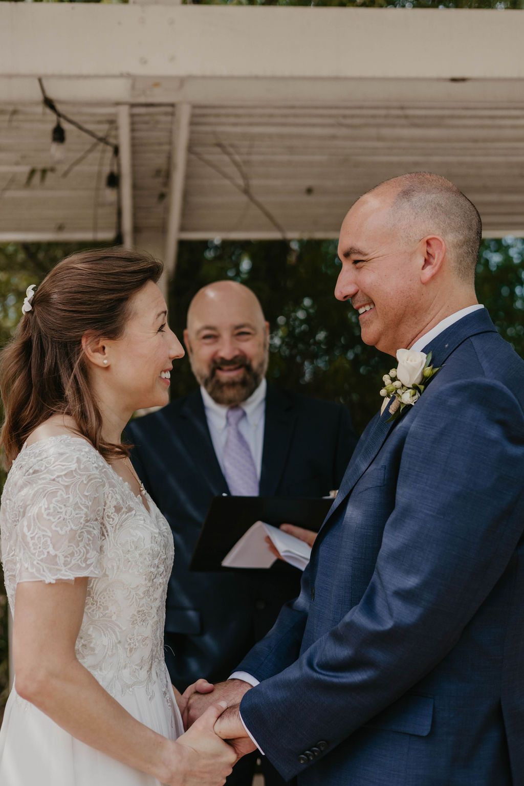 A joyful wedding ceremony taking place under a white gazebo with an officiant.