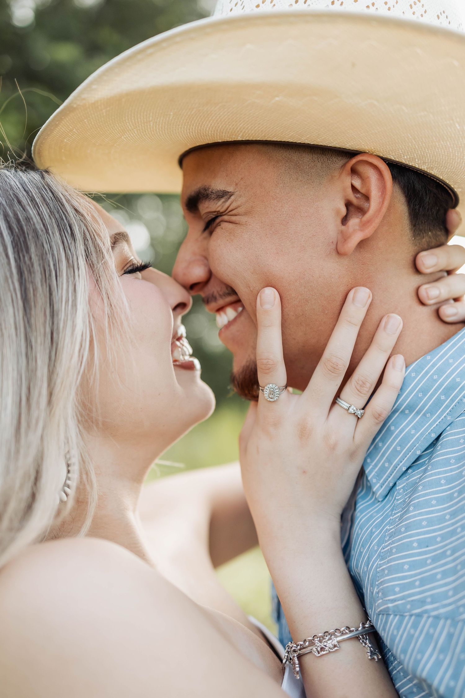 Couple sharing intimate moment outdoors with one wearing cowboy hat.