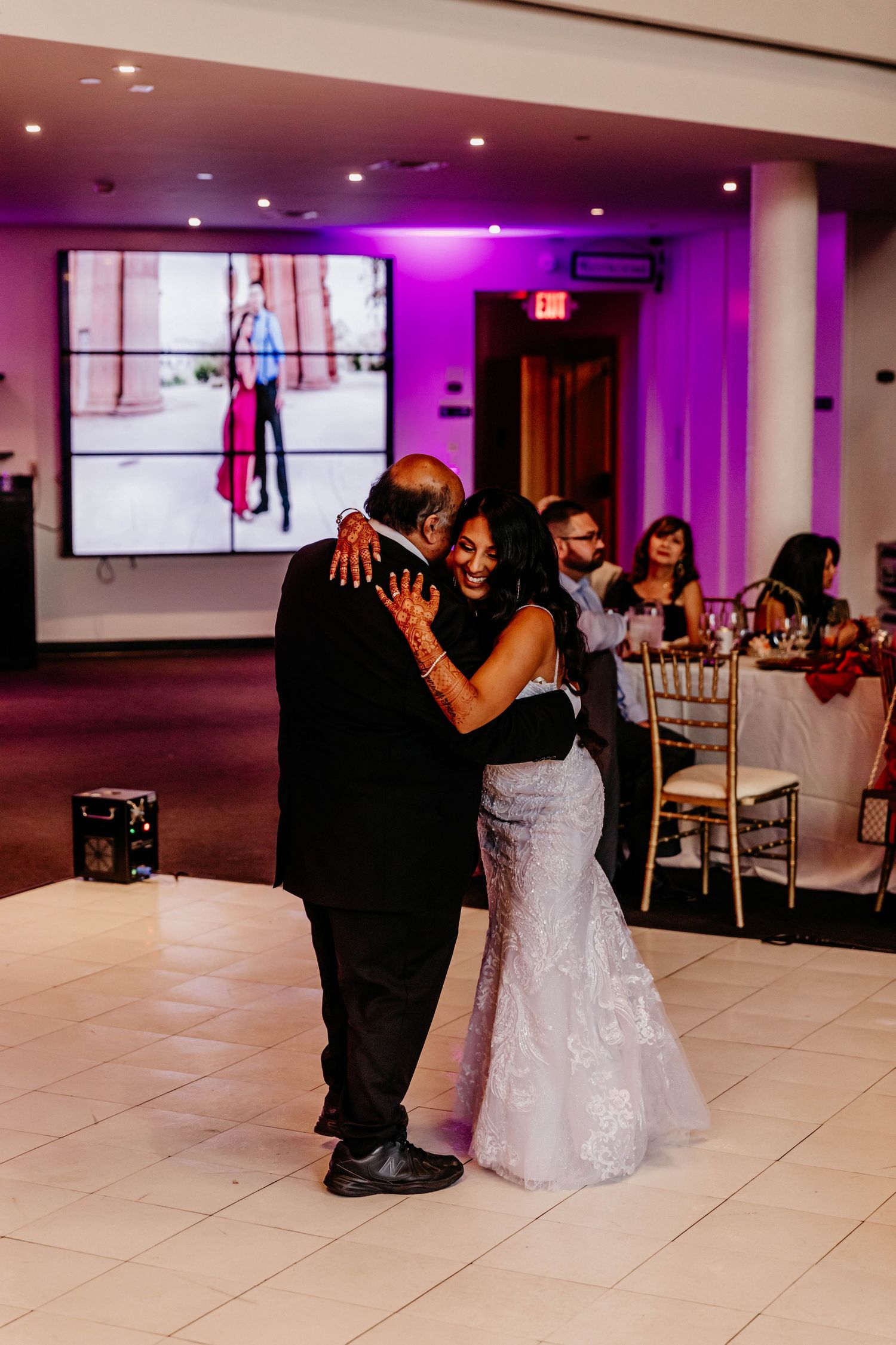 A special dance moment captured during a wedding reception with purple lighting.