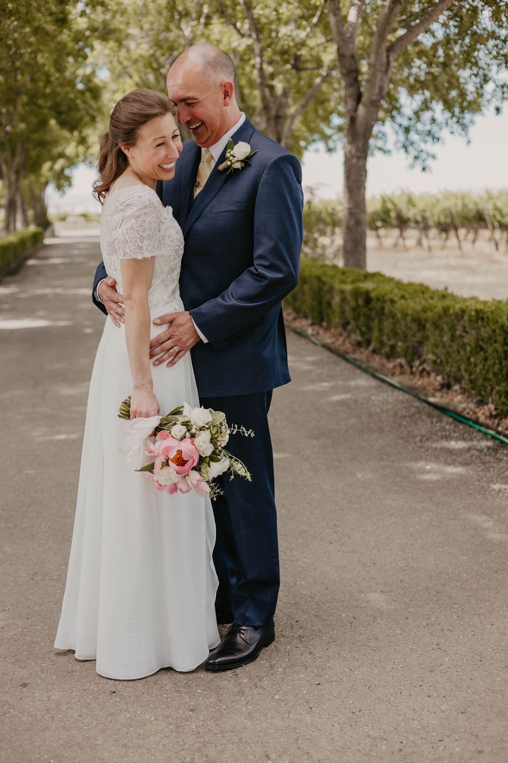 Romantic wedding portrait on garden path with pink bouquet and lace detail dress.