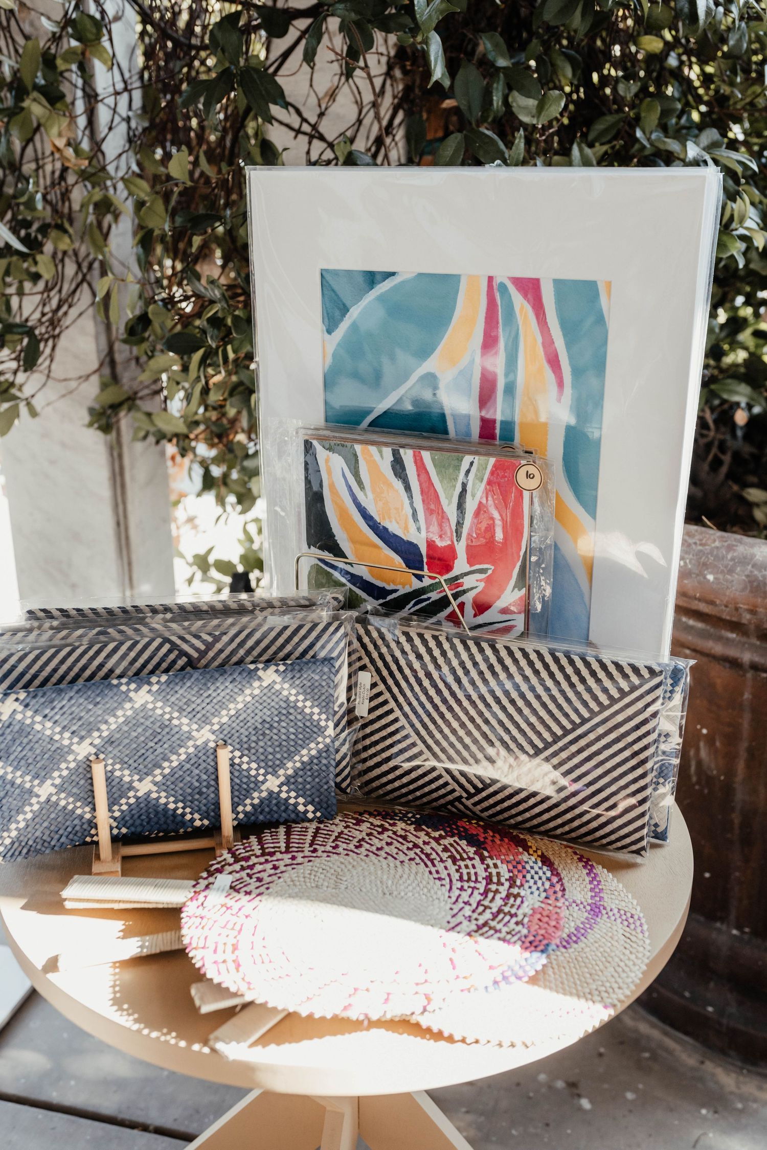 Modern display of geometric patterned throw pillows and artwork on a round table with natural foliage backdrop.