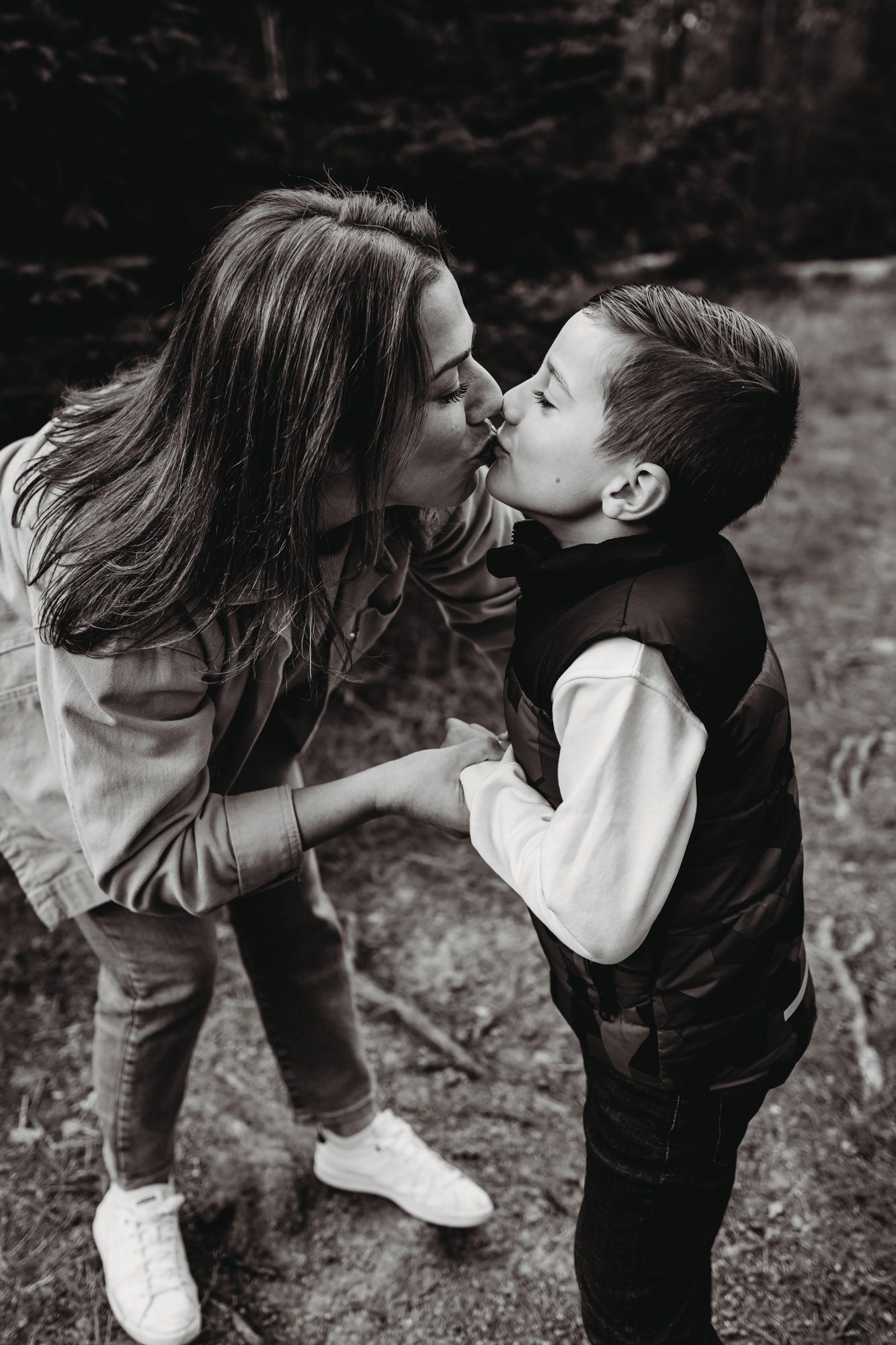 Black and white photo showing an affectionate moment between parent and child on forest trail.