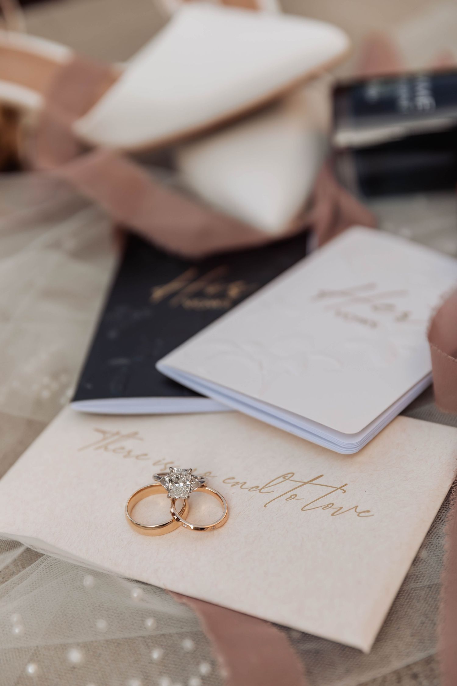 Wedding stationery and rings arranged on neutral background.