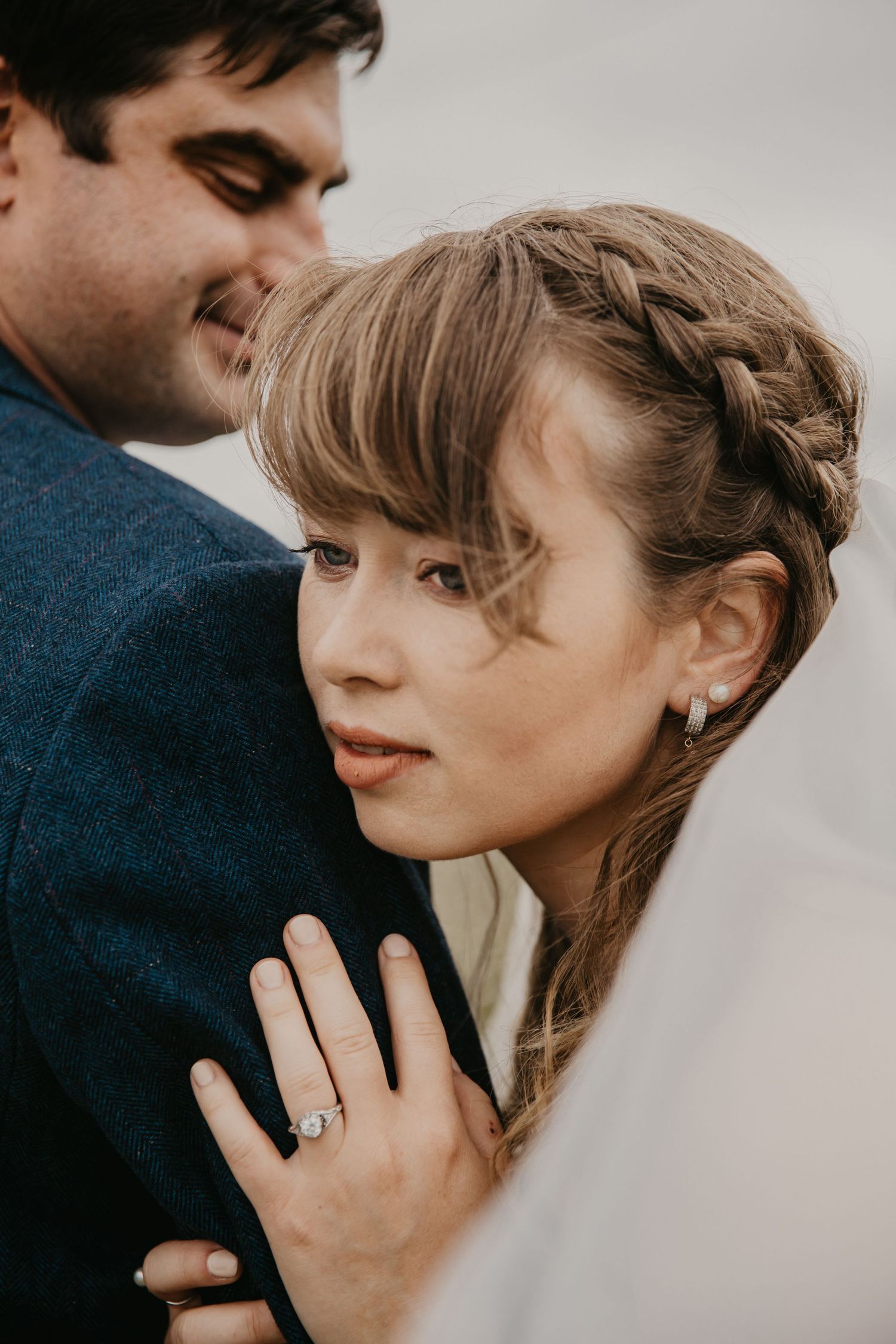 Romantic close-up engagement photo showing hands with ring in soft lighting.