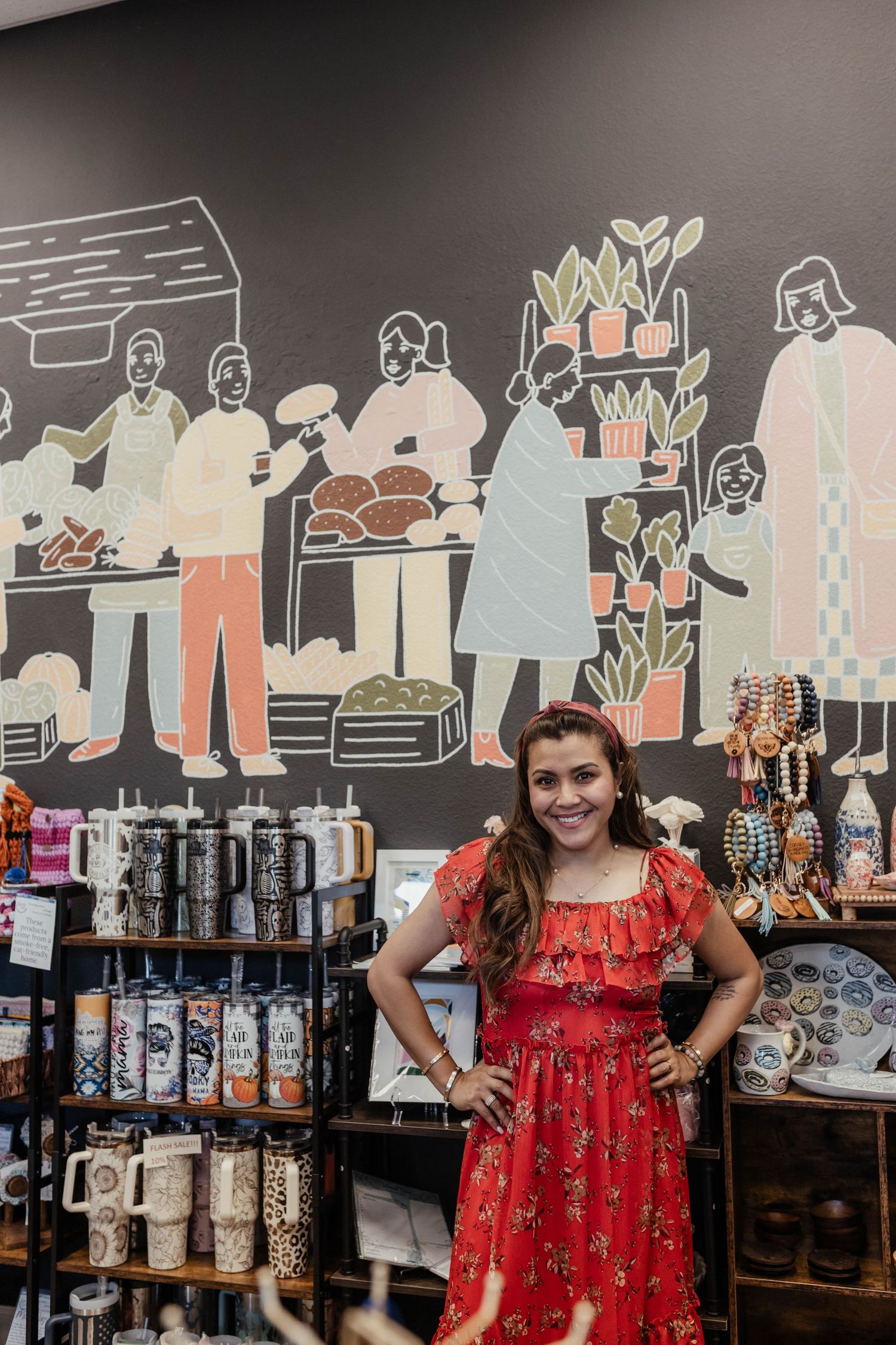 A red floral dress against a wall decorated with artistic line drawings in a retail setting.