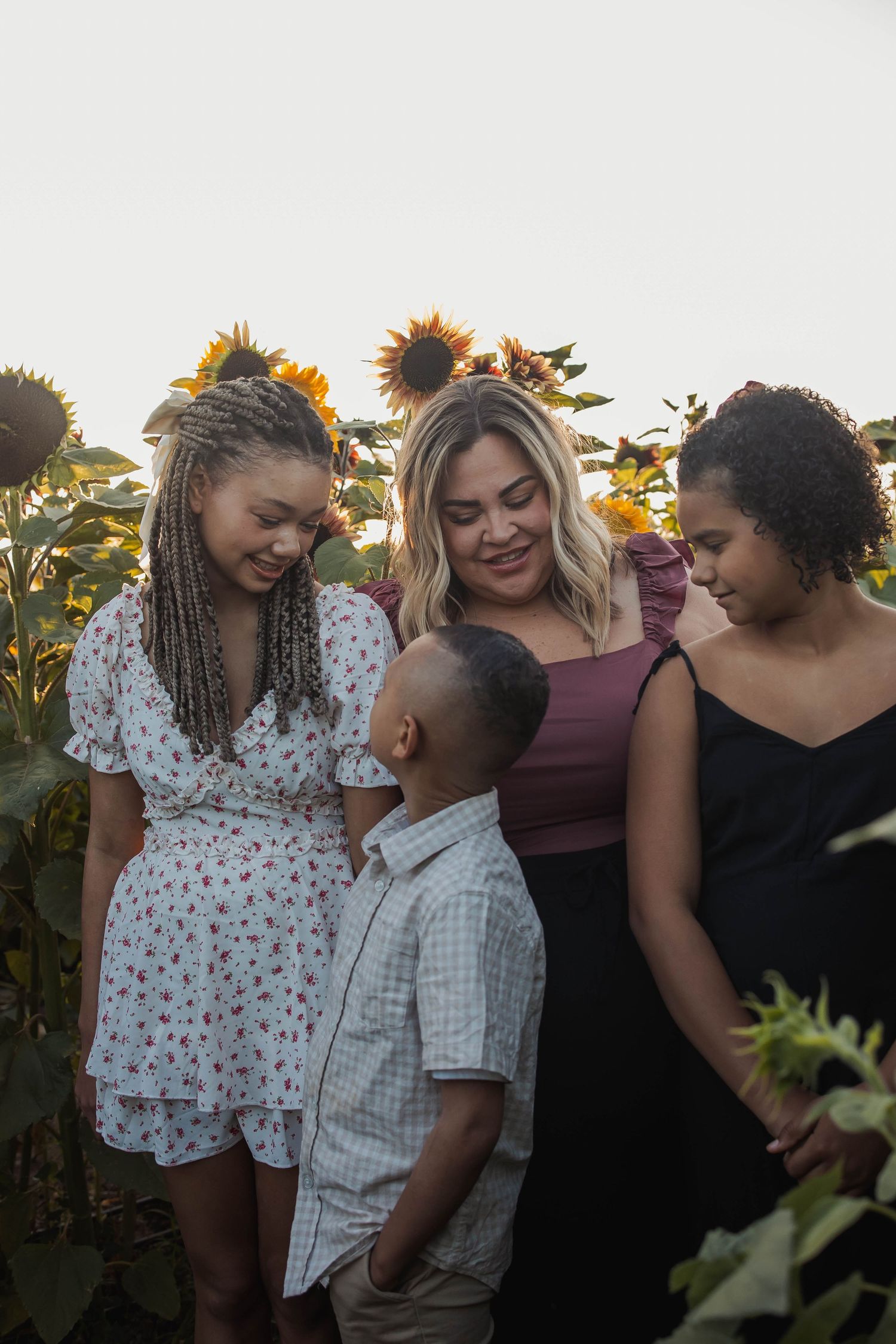 Intimate gathering of friends posing together in a sunflower garden at dusk.