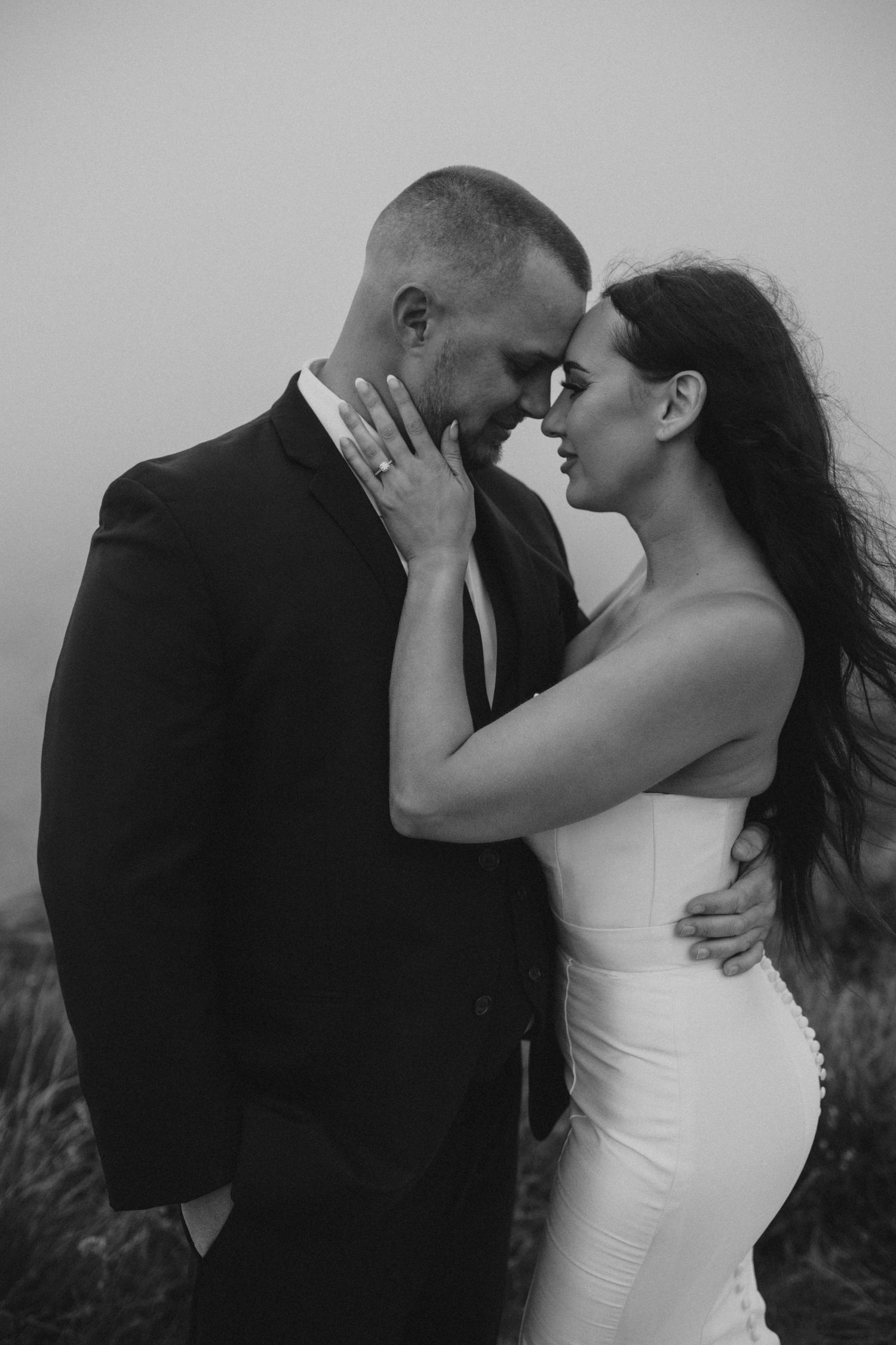 An intimate black and white portrait of a wedding couple in a tender embrace.