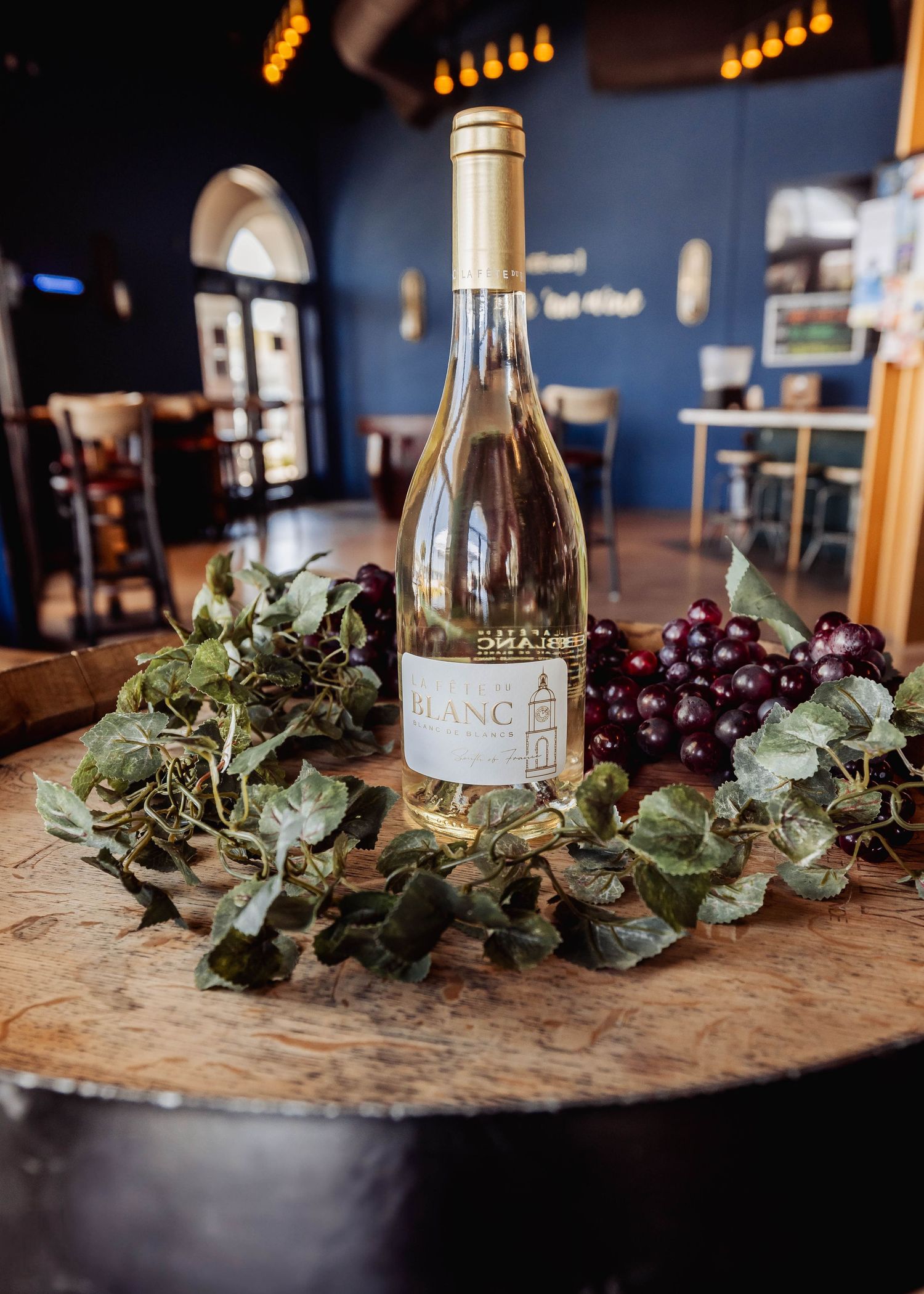 Wine bottles and decorative eucalyptus branches arranged on rustic wooden surface with ambient lighting.