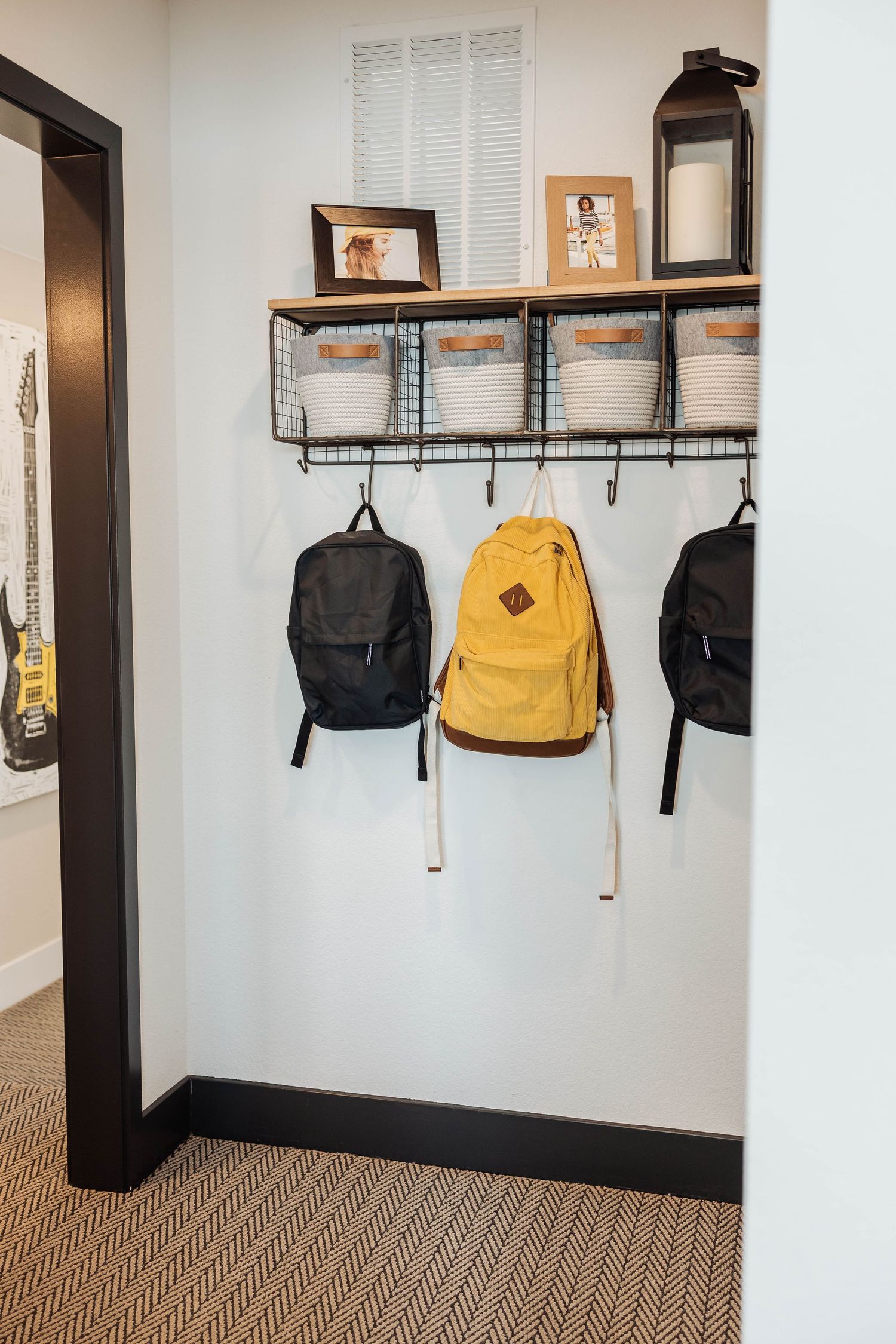 Wall-mounted coat hooks with backpacks and storage shelves in a minimalist hallway.