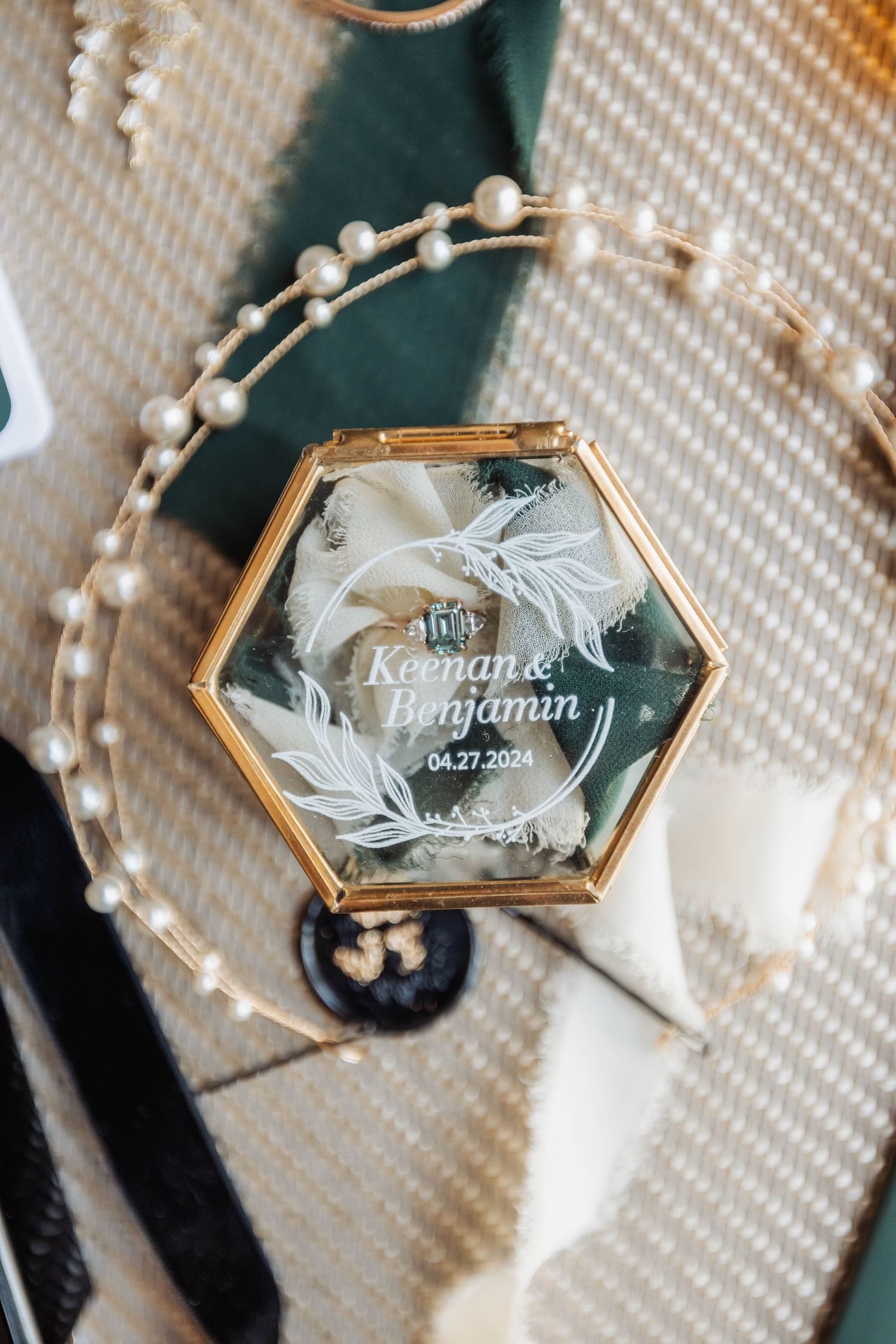 Hexagonal glass wedding ring box with delicate gold details and engraving.