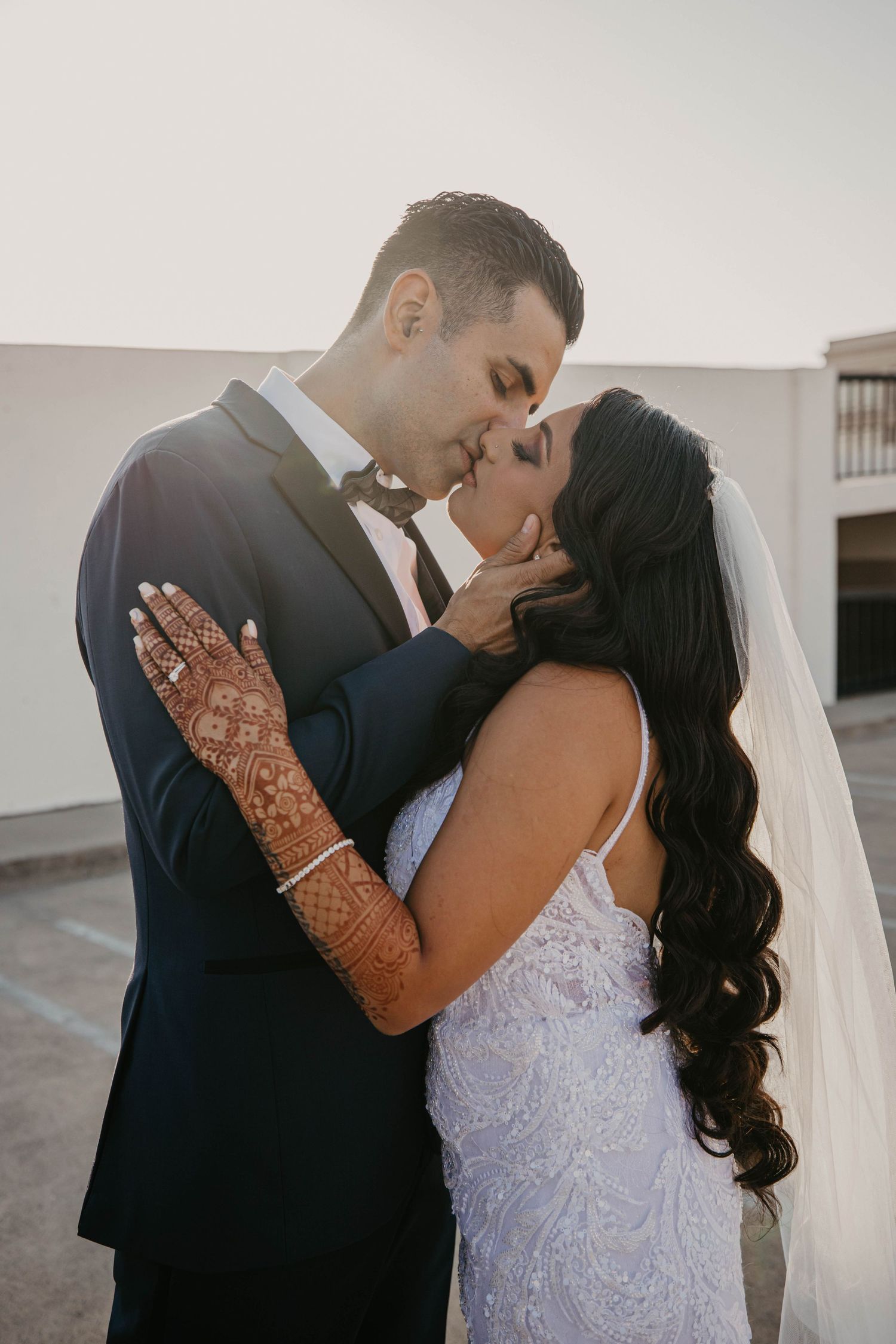 Romantic couple shares intimate kiss during wedding photoshoot at sunset.