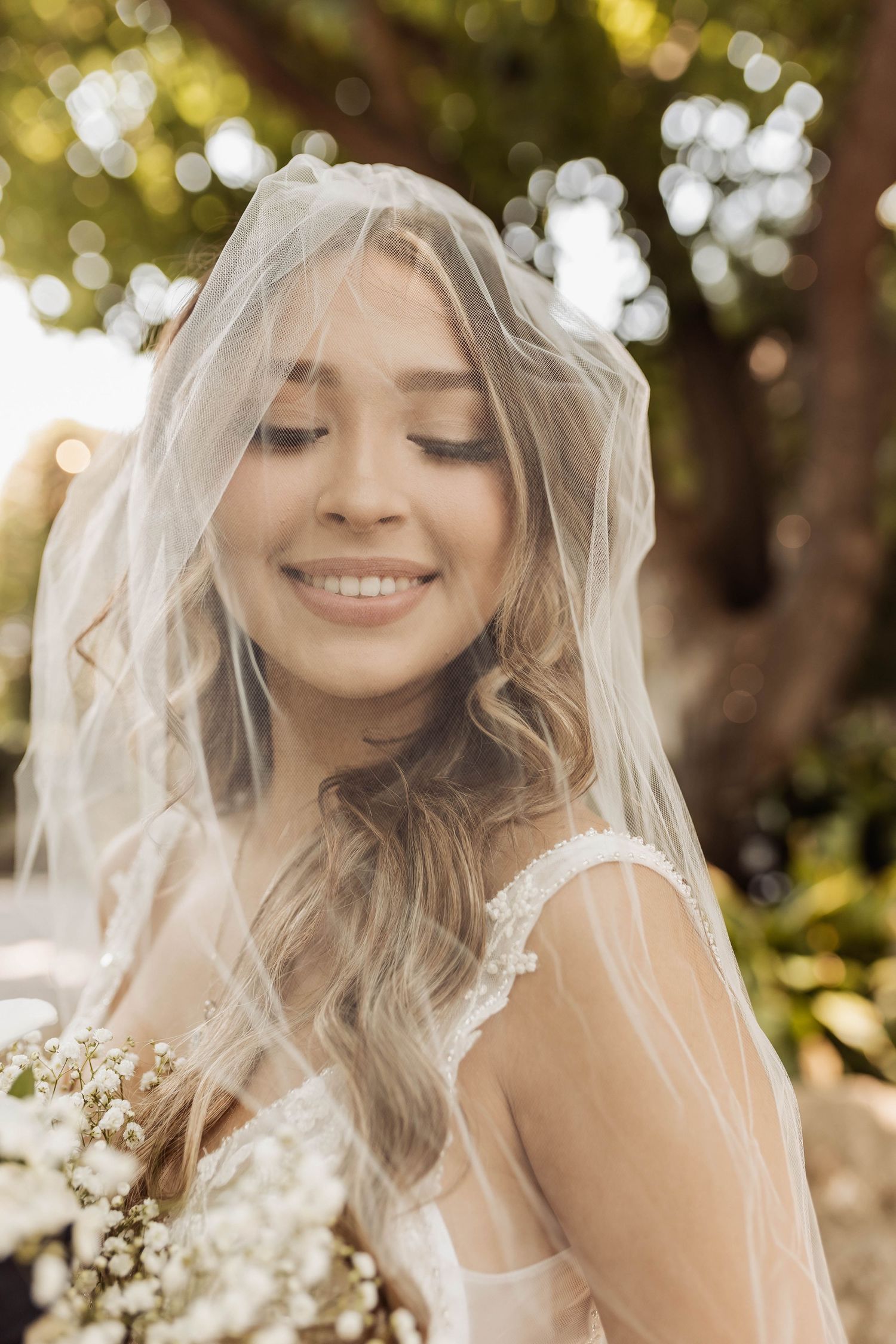 Close-up bridal portrait through delicate veil with soft bokeh background.
