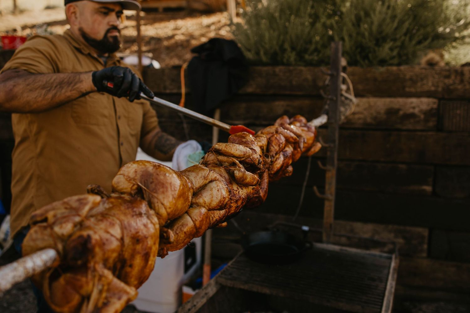 Grilled meat on a rotisserie spit over an outdoor fire pit.