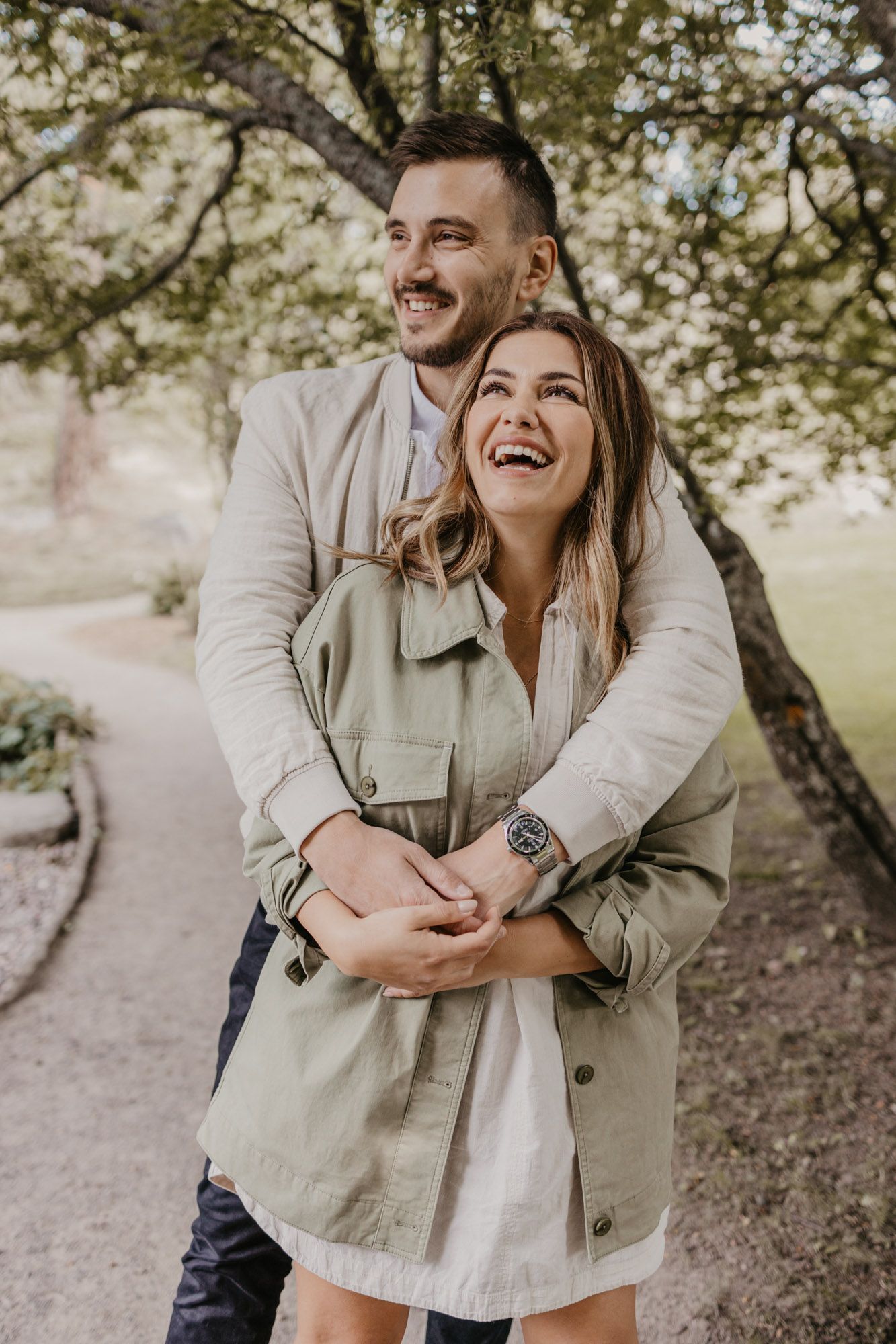 A happy couple laughs together while embracing on an outdoor trail.