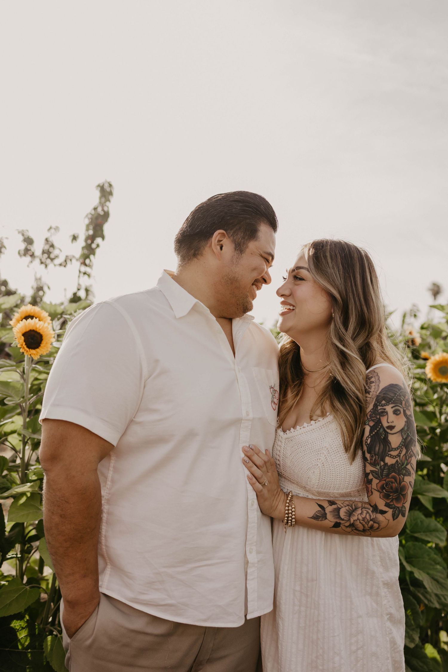 A couple shares a romantic moment in a sunflower field during sunset.
