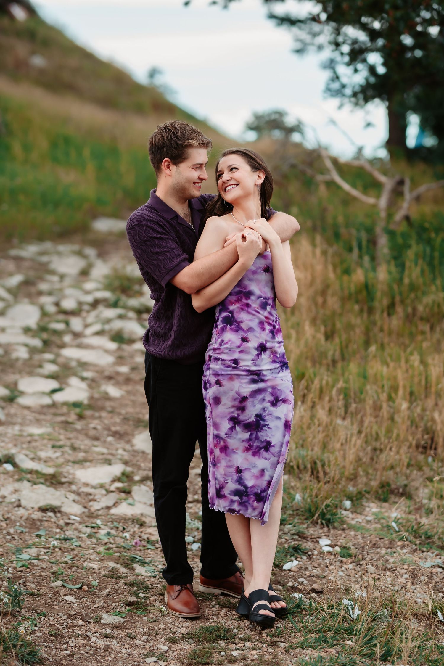 A sweet couples photoshoot along a rocky mountain trail with one person in a purple dress.
