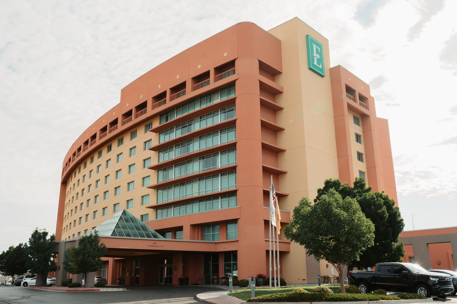 Modern hotel exterior with curved pink and turquoise architecture and multiple floors.