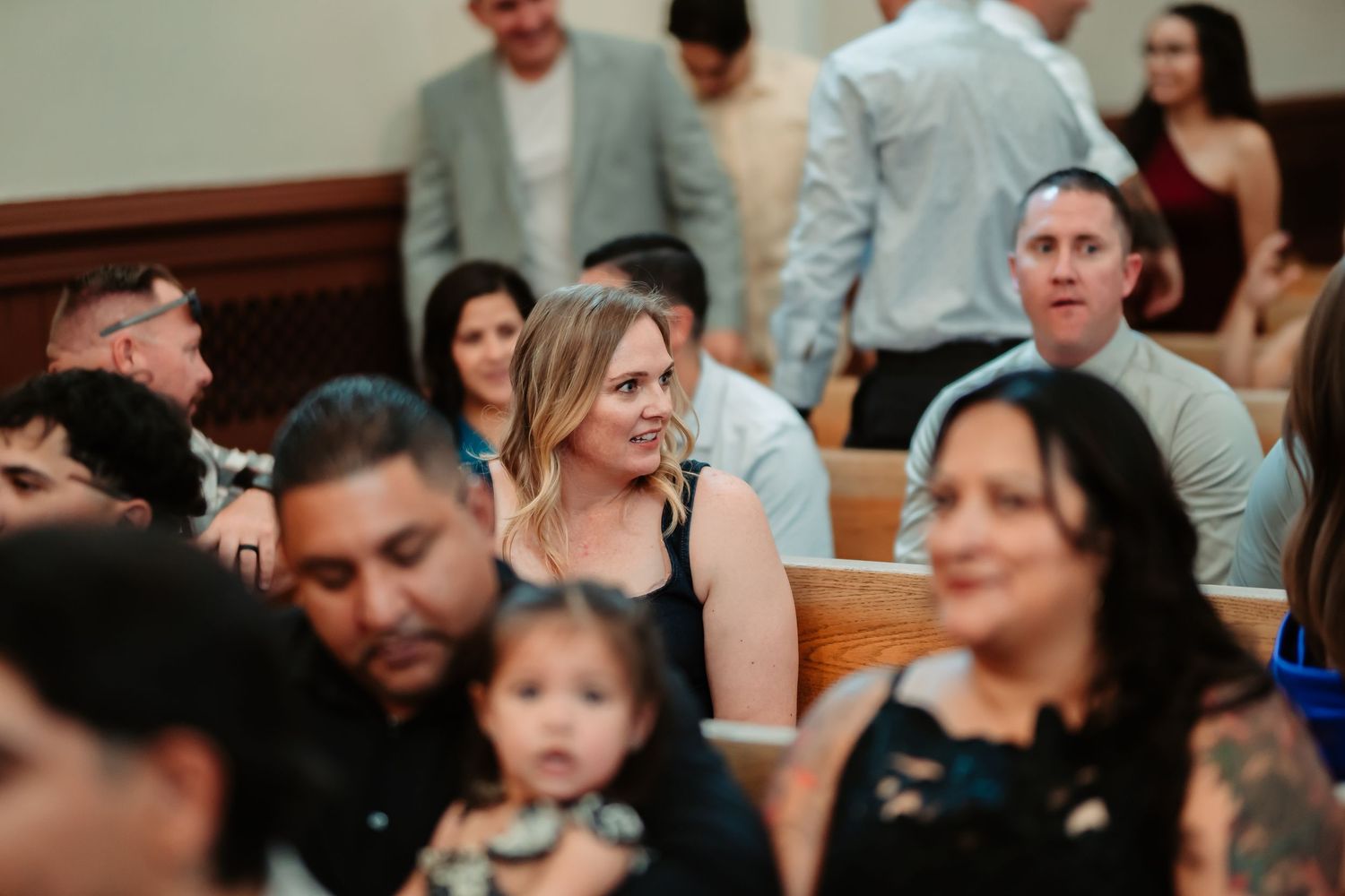 Church congregation members sitting in wooden pews during a religious service.
