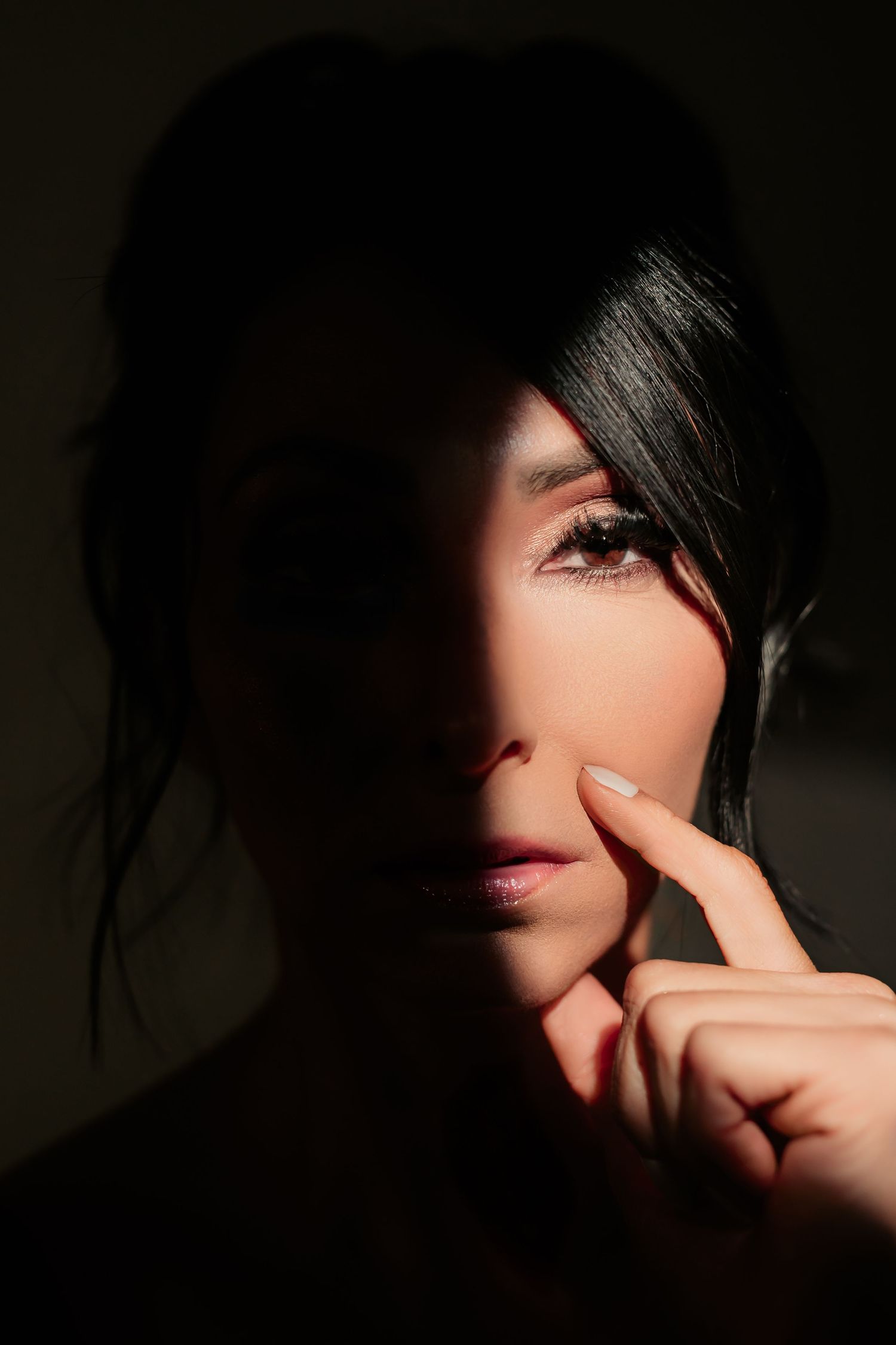 A dramatic sequence of dark artistic portraits showing a finger pointing gesture against shadows and light.