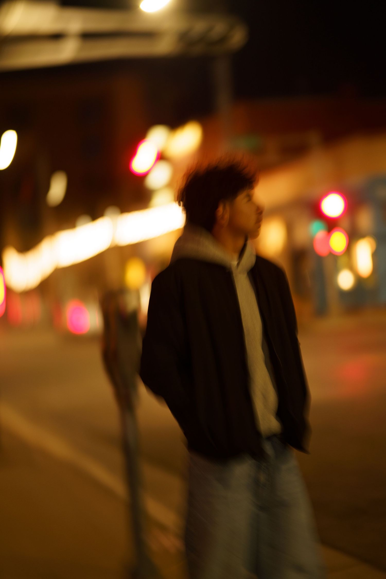 Silhouettes of people walking at night on a city street illuminated by blurred bokeh lights.