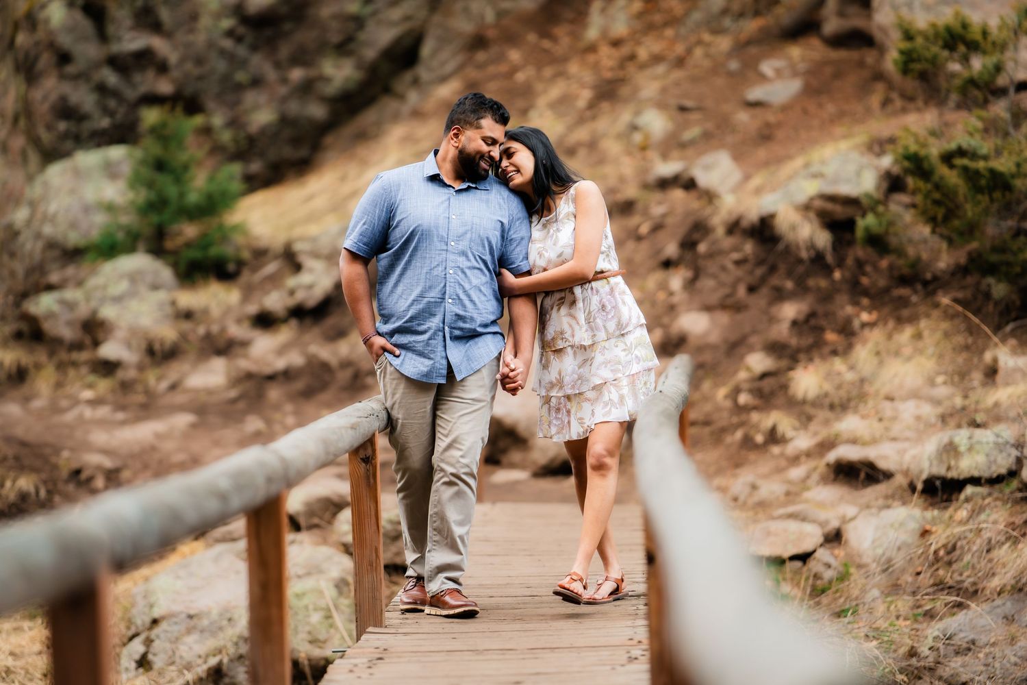 A couple embraces on a wooden boardwalk path with rustic canyon walls in the background.