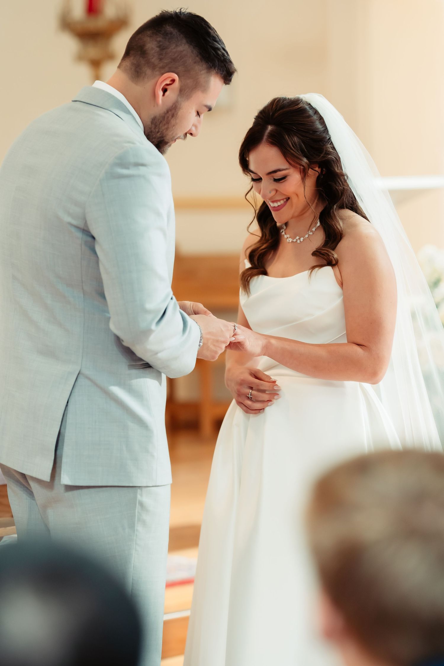 A couple shares an intimate moment during their wedding ceremony in a light-filled venue.