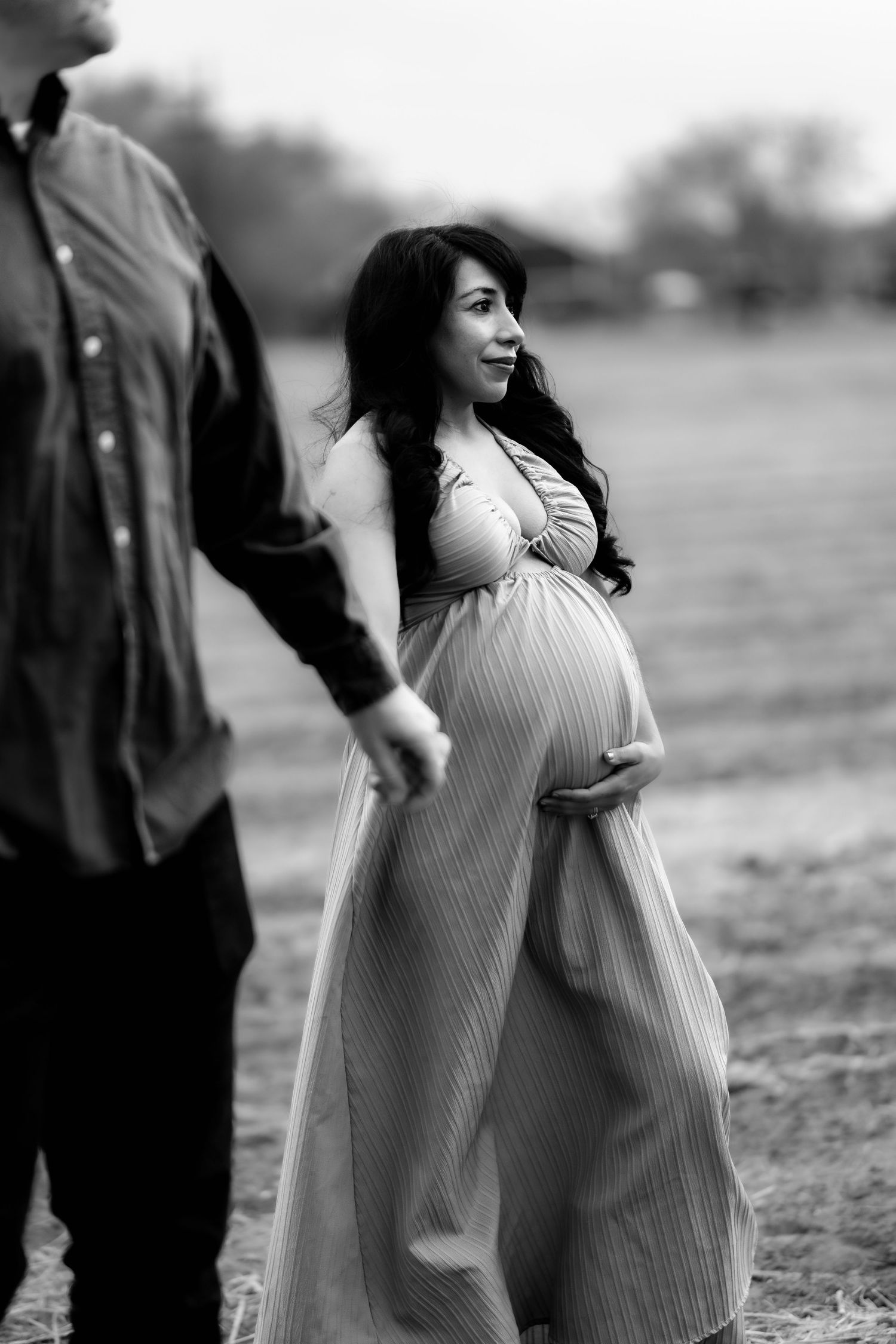 A black and white photo series shows a woman in a flowing striped dress walking through a field.