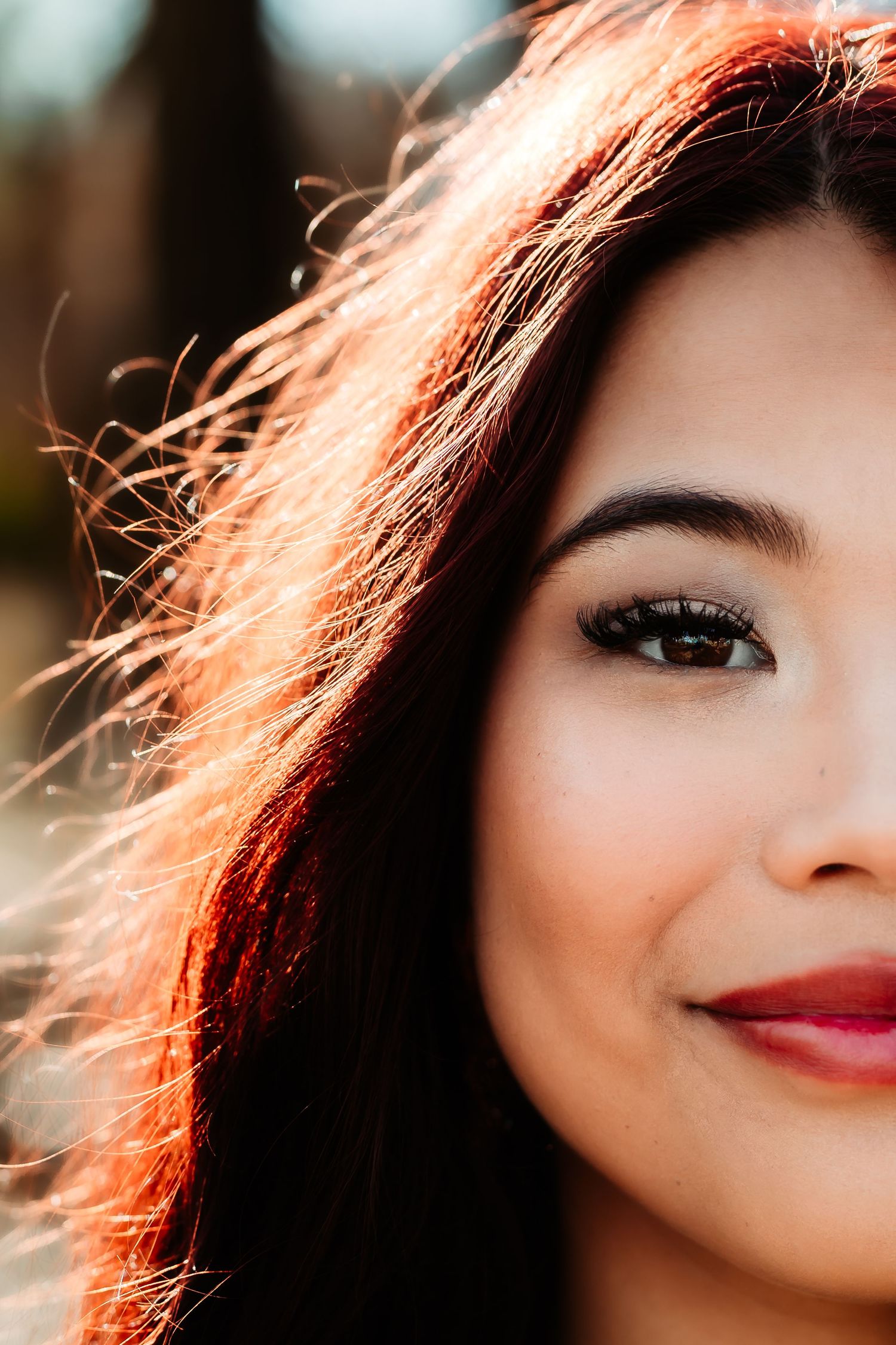 Close up portrait with warm backlit hair and red lipstick creating a dreamy, ethereal effect.