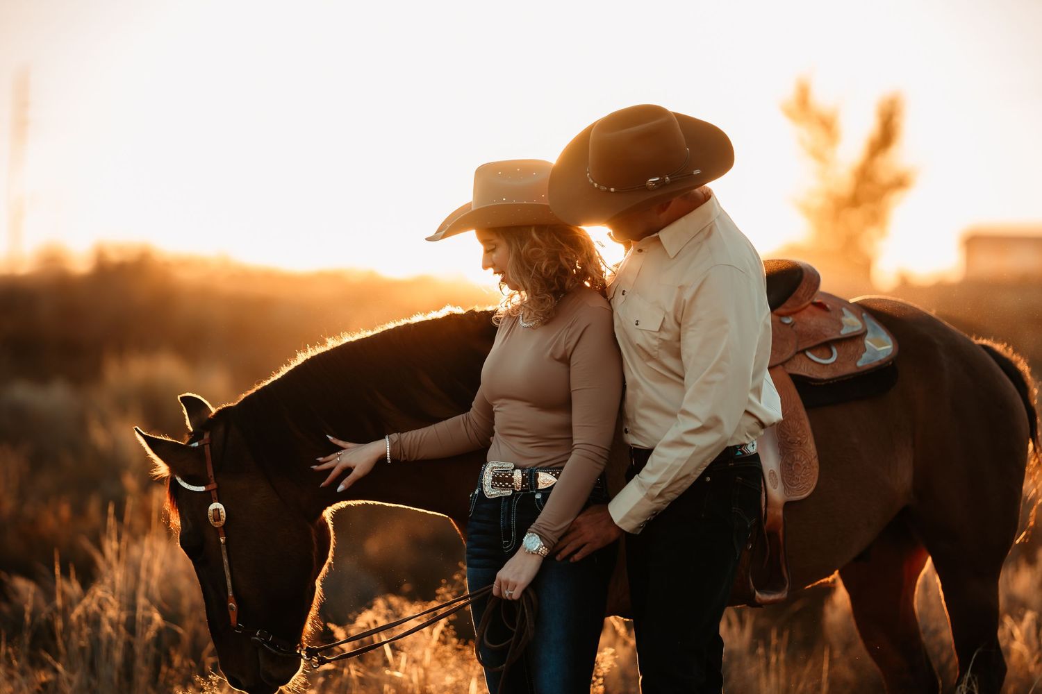 A silhouetted figure in a cowboy hat tends to horses in a golden sunset field creating a dramatic western scene.