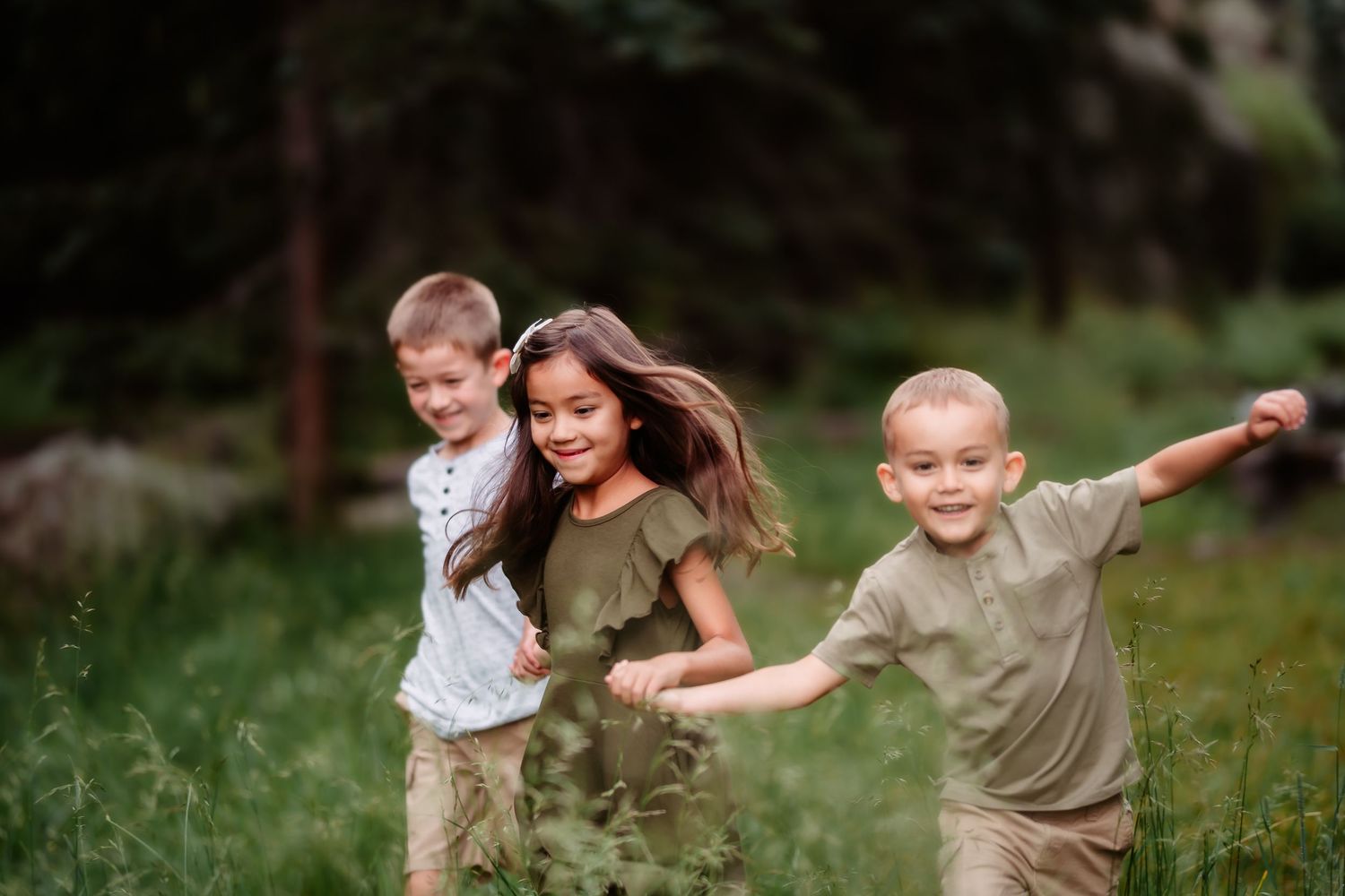 Children play and run together outdoors in a grassy field on a summer afternoon.