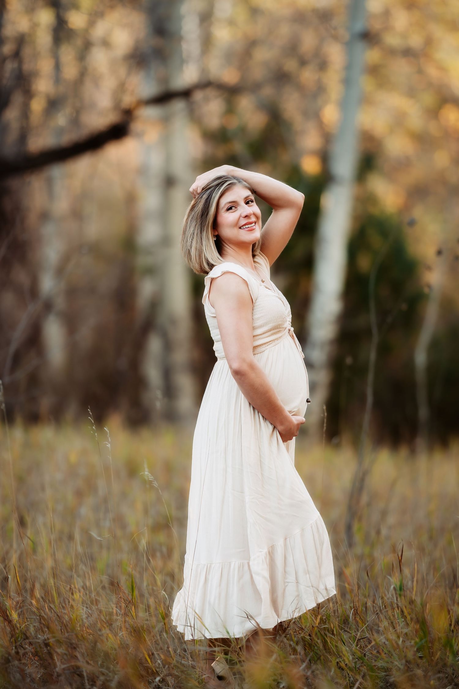 Ethereal outdoor maternity photos showing flowing white dress against autumn foliage background.