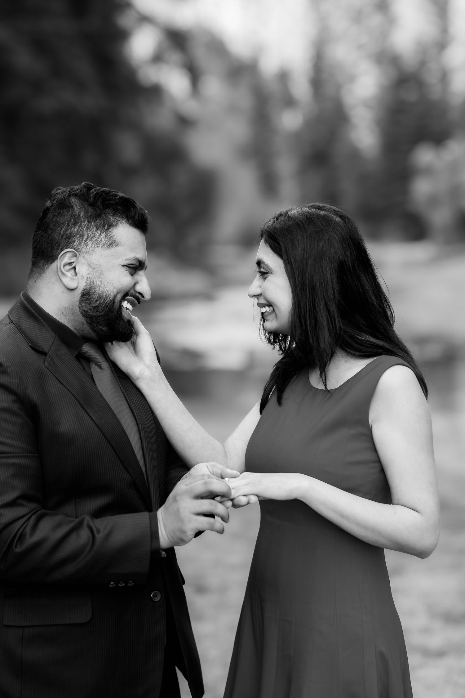 A romantic engagement moment captured in black and white as a couple exchanges rings.