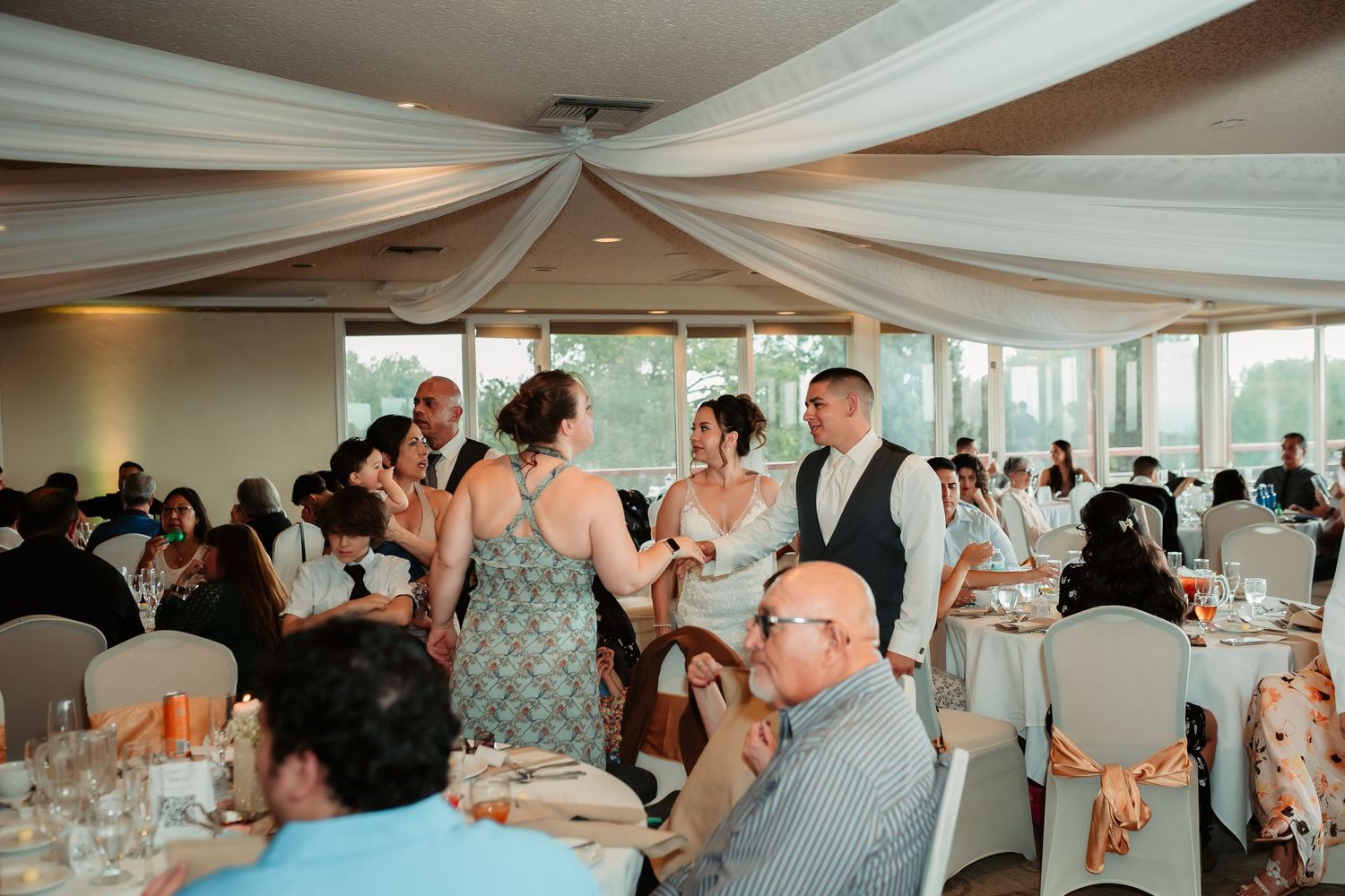 Elegant wedding reception hall with white draped ceiling and formal table settings.