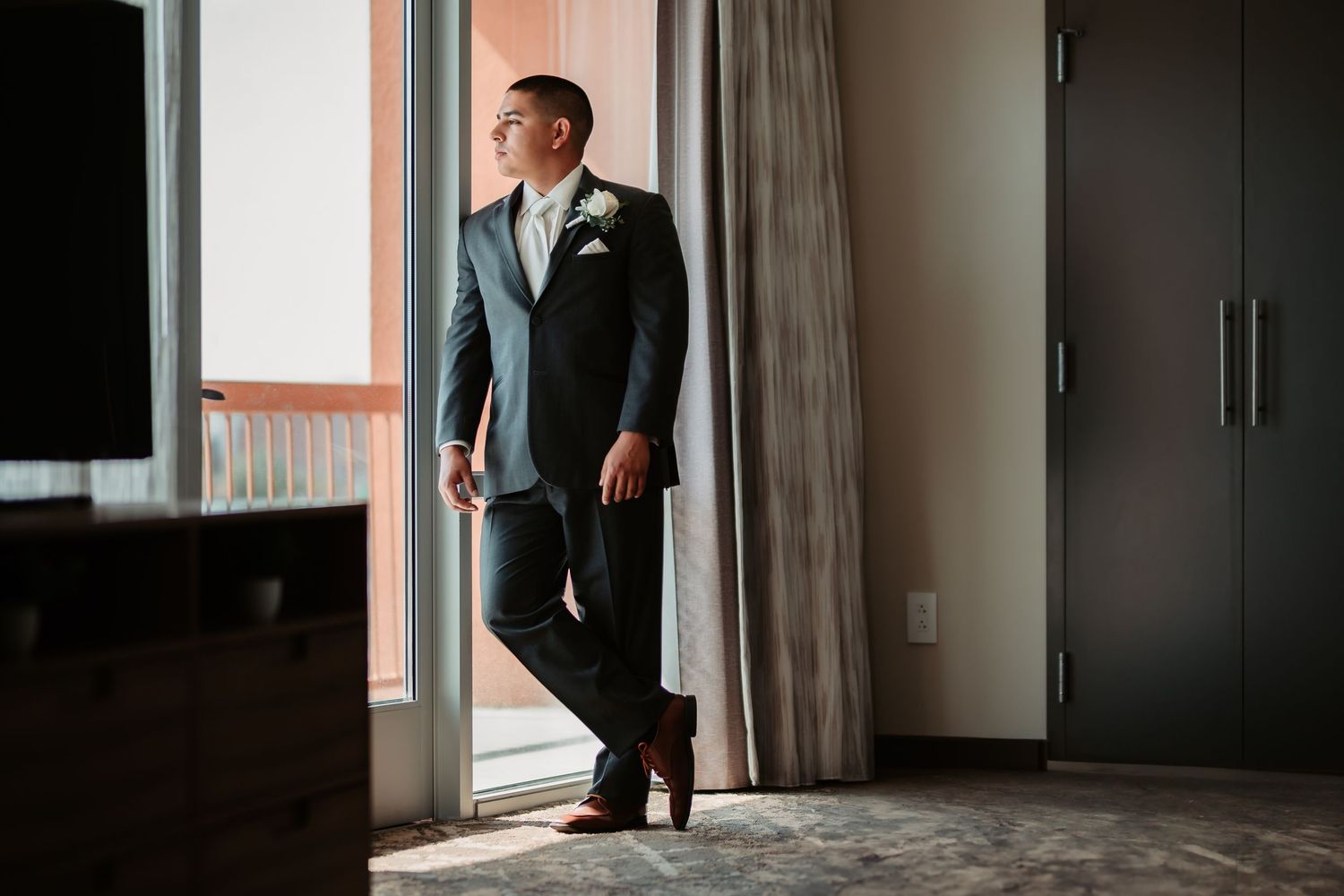 A sequence of wedding photos showing two men talking in a hallway with natural lighting.