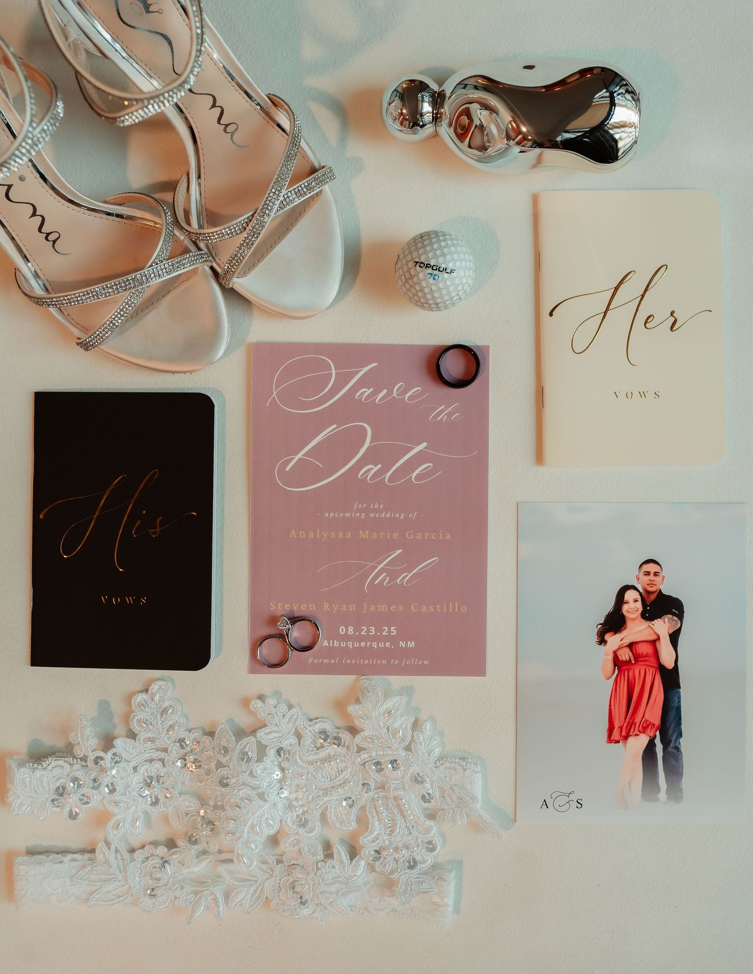 Wedding invitations and decor in soft pink tones with silver rings and delicate lace details laid out on a neutral surface.