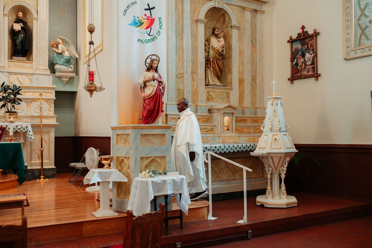 Interior panorama of a historic church with ornate white walls, religious statues, and decorative artwork.