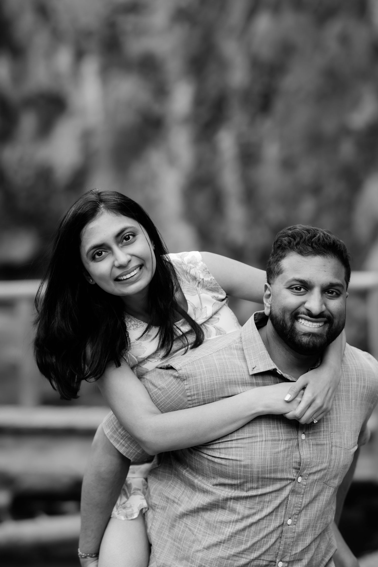 A joyful couple sharing a piggyback ride moment outdoors against a rocky backdrop.