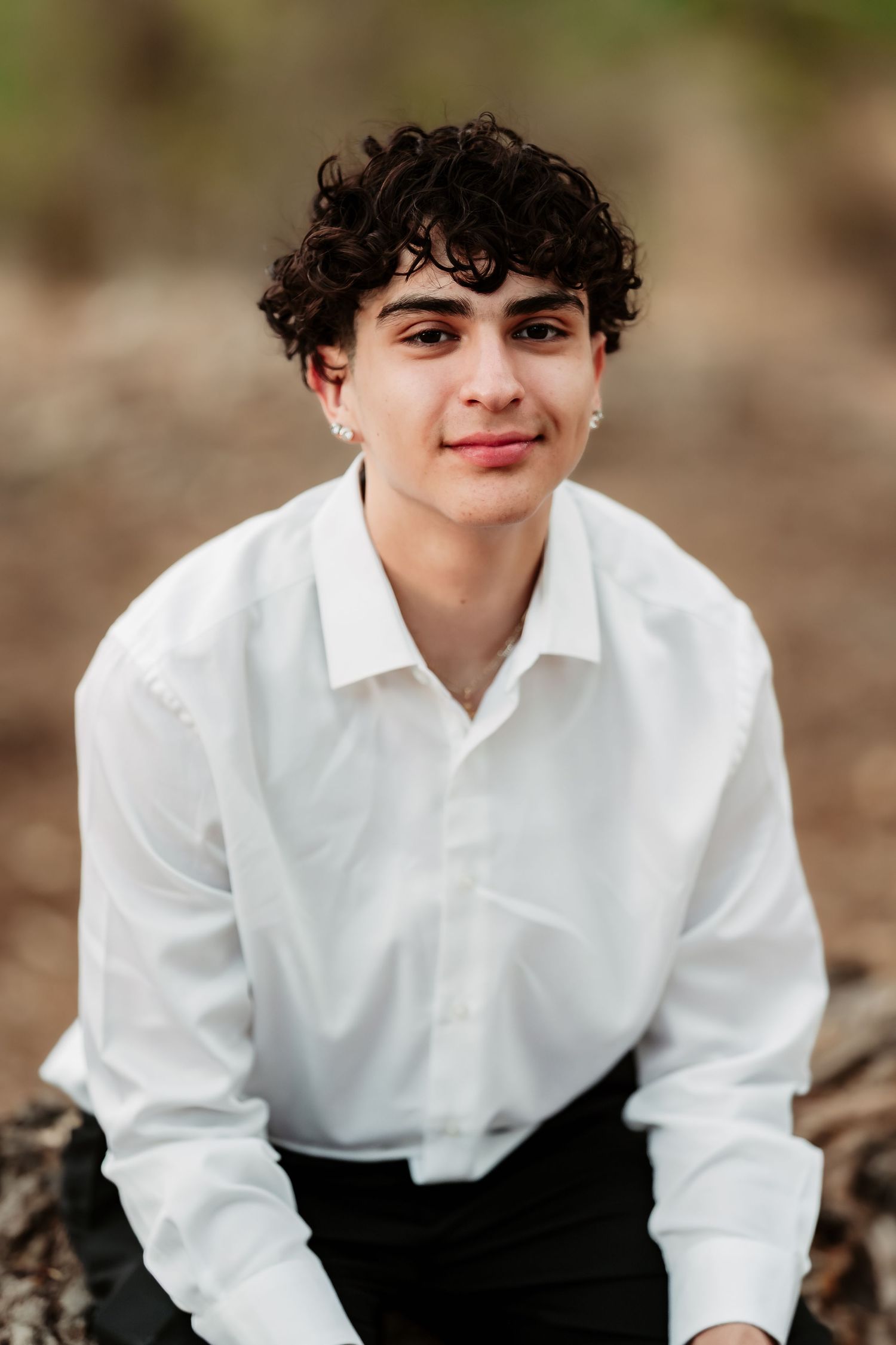 Portrait of someone in a crisp white dress shirt and dark trousers against a natural background.