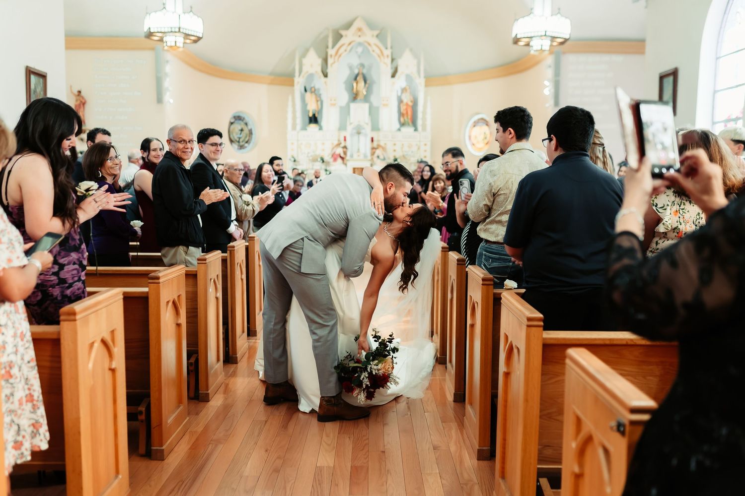 Wedding ceremony attendees sit in wooden church pews during a traditional service.
