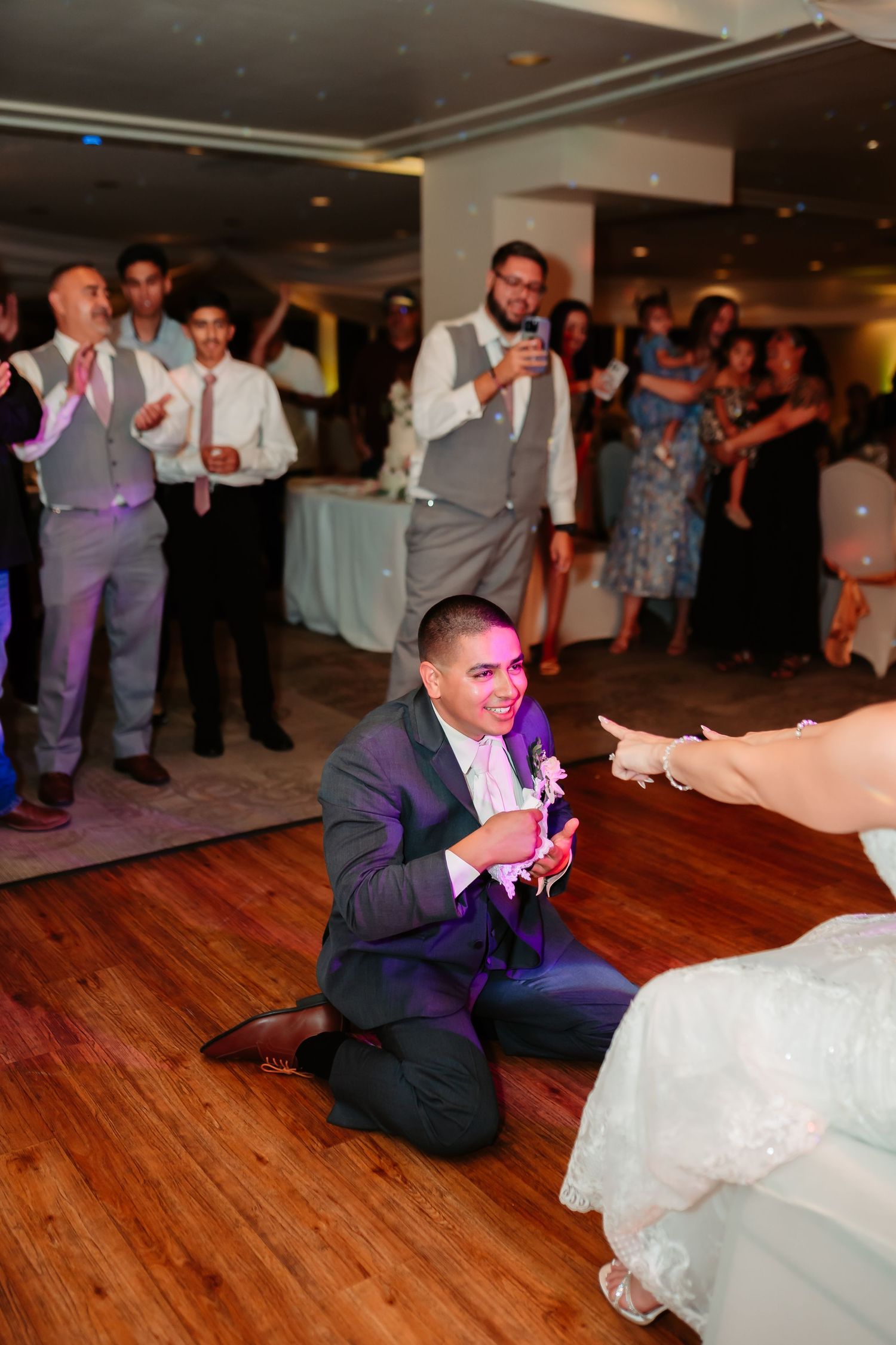 Wedding guests cheer and take photos during a reception celebration.
