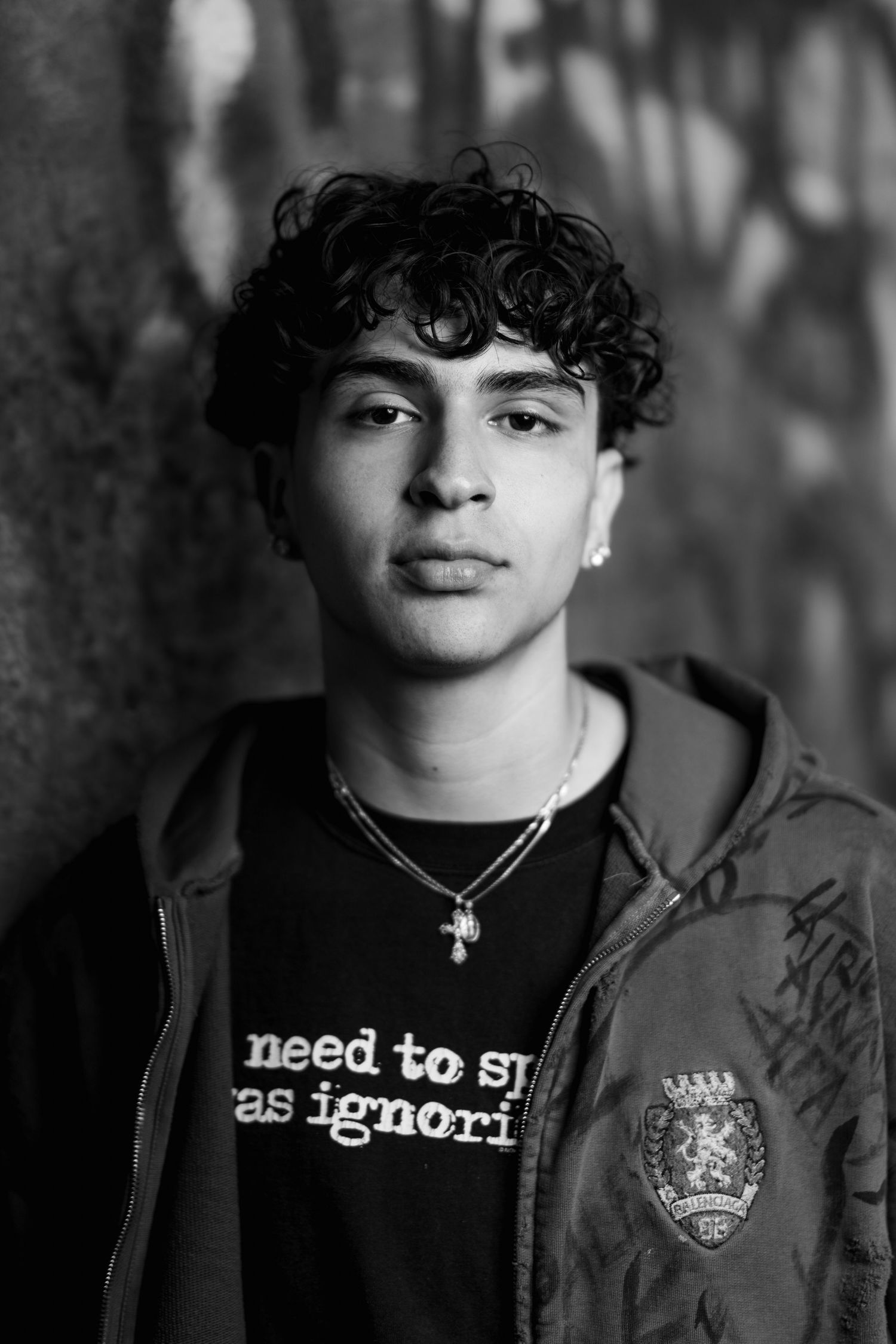 Black and white closeup portrait of person wearing necklace and casual attire.