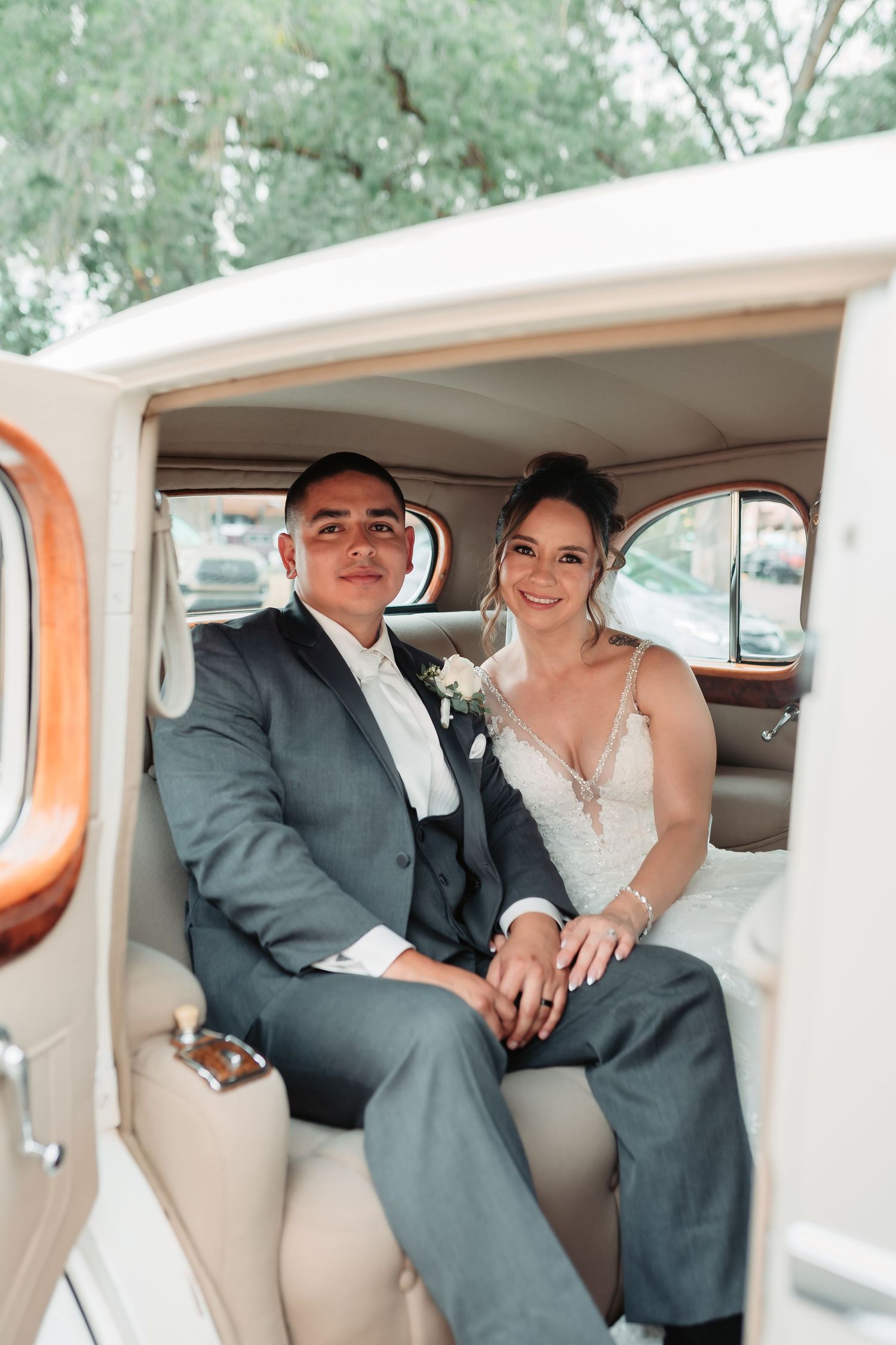 A couple sharing intimate moments in the backseat of a classic car on their wedding day.