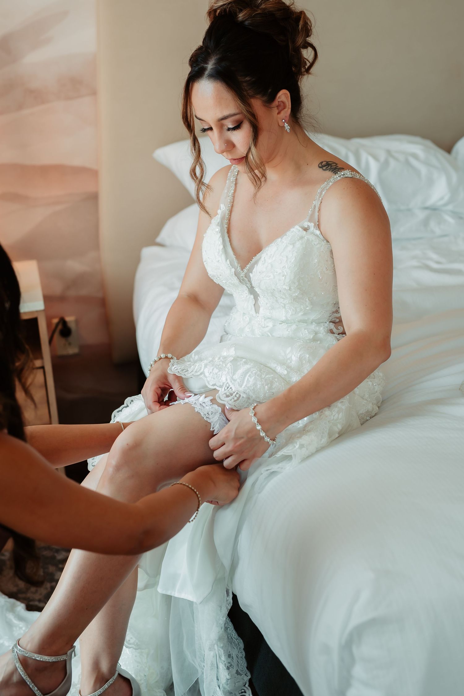Wedding preparation scene showing final adjustments to a white lace bridal gown.