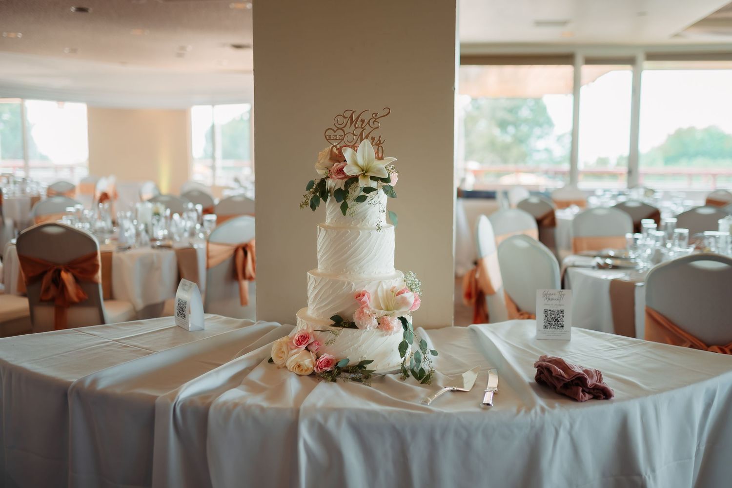 Wedding reception tables decorated with coral floral centerpieces and white linens in an elegant banquet room.
