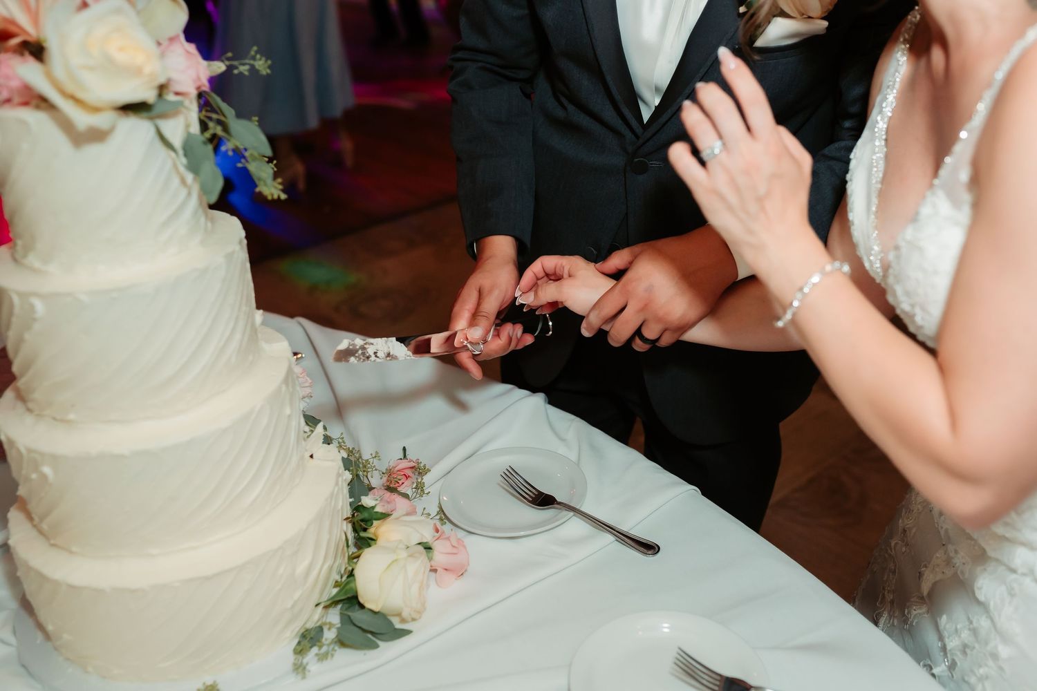 Newlyweds cutting their white wedding cake together at the reception.