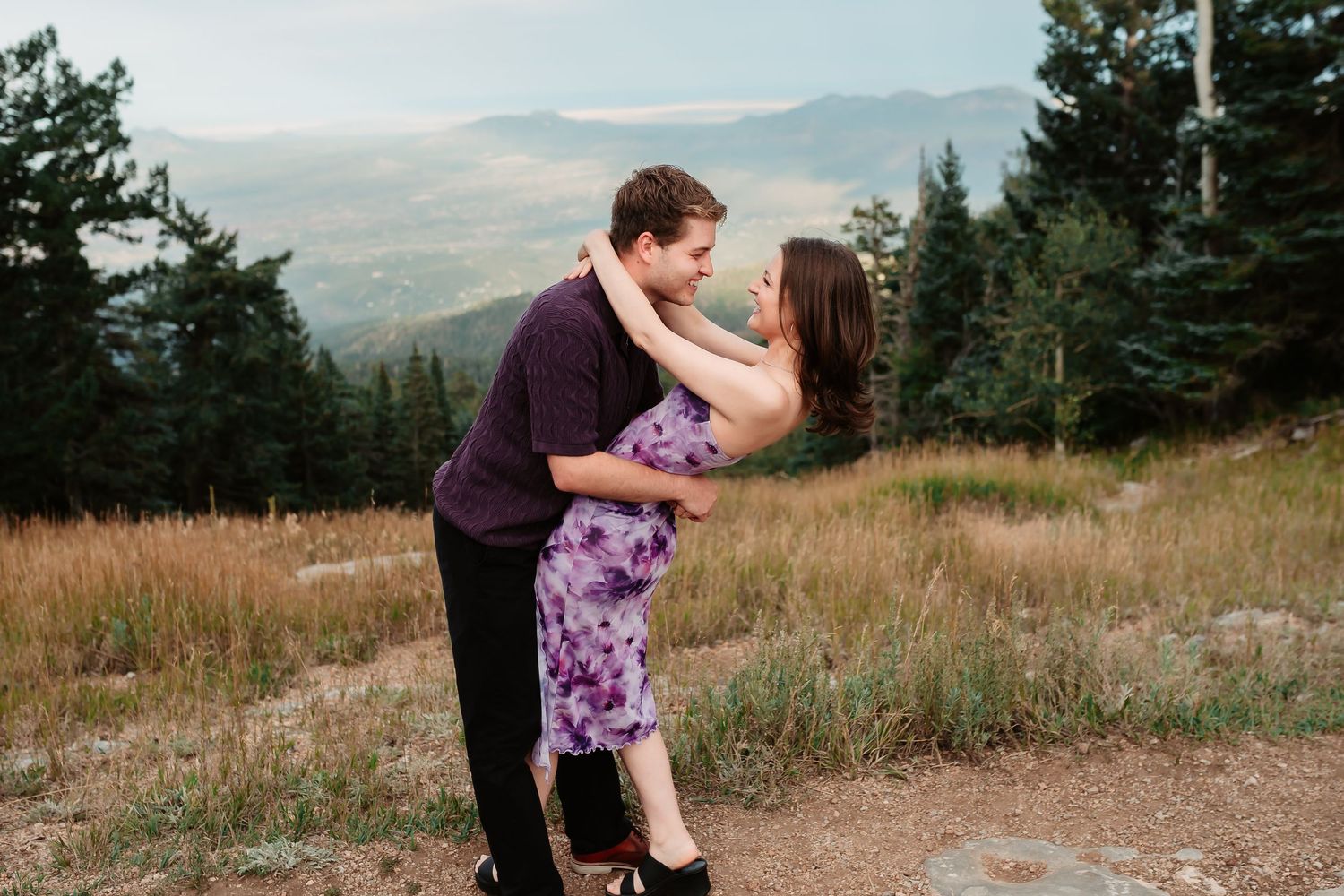 Panoramic mountain engagement photos showing couple in romantic poses against natural backdrop.