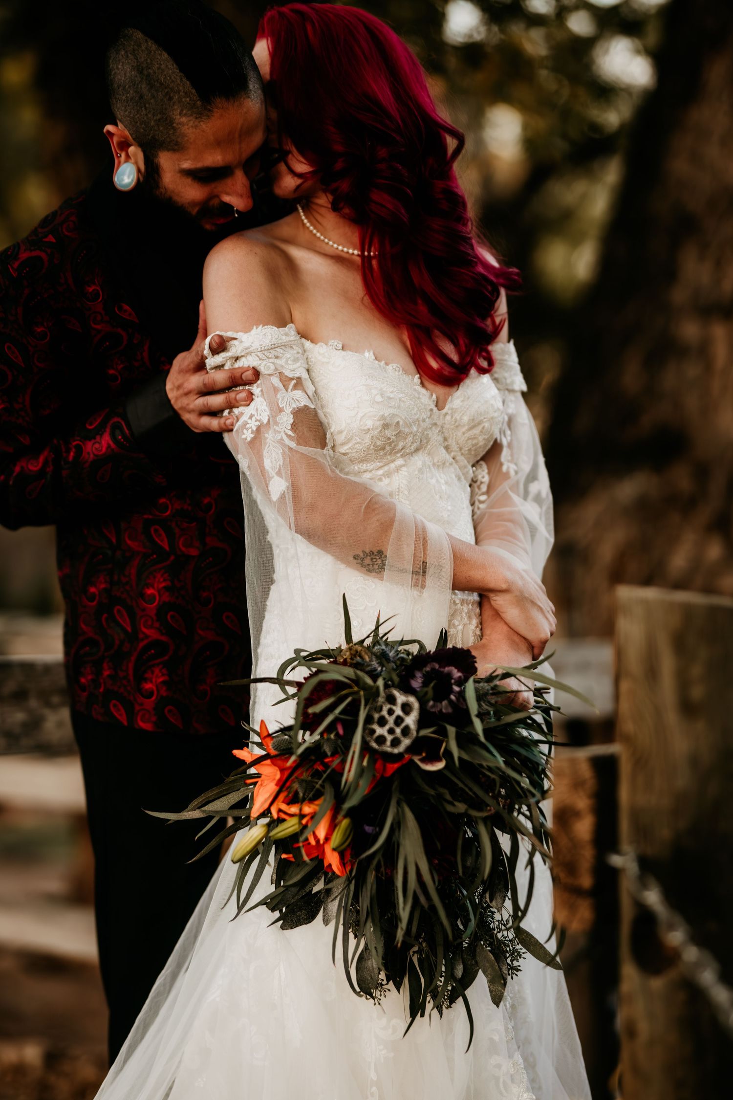 A romantic wedding photoshoot showing details of a white lace dress and a tropical style bouquet with red flowers.