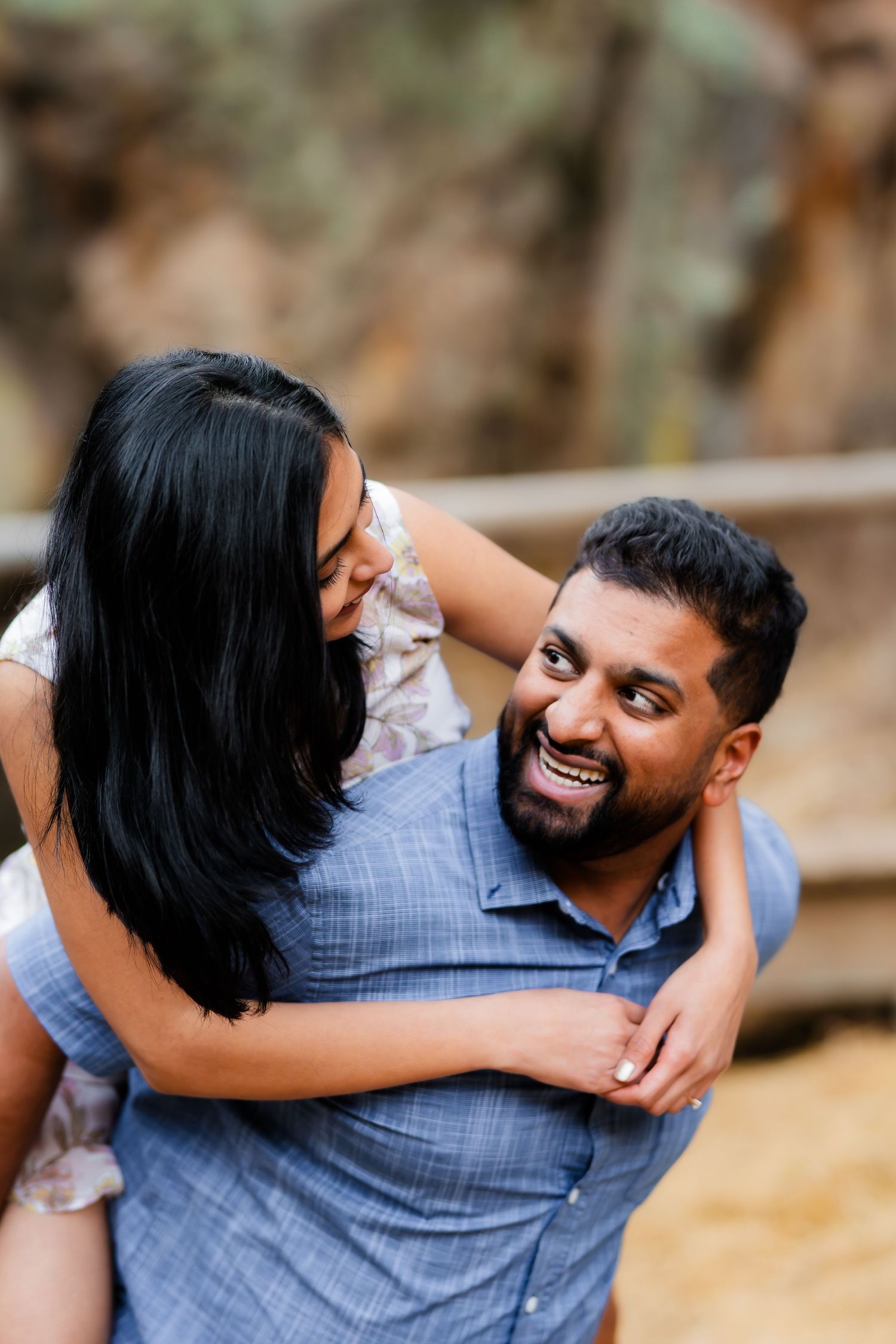 A joyful piggyback ride moment captured between a couple in casual attire outdoors.