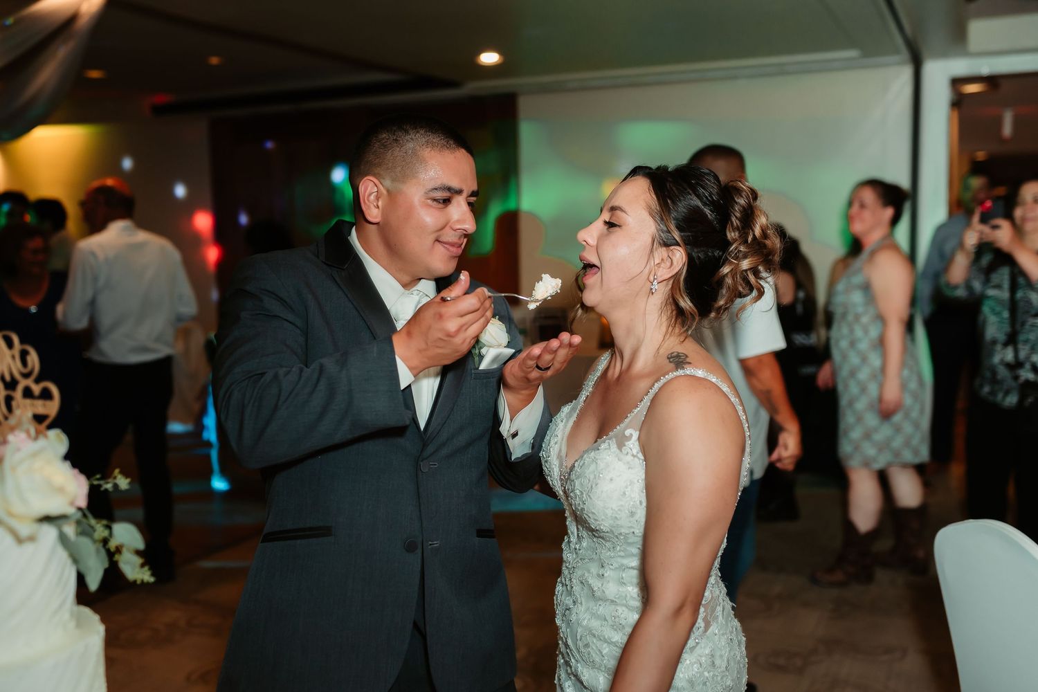 Couples dance intimately on the dimly lit reception dance floor under soft lighting.
