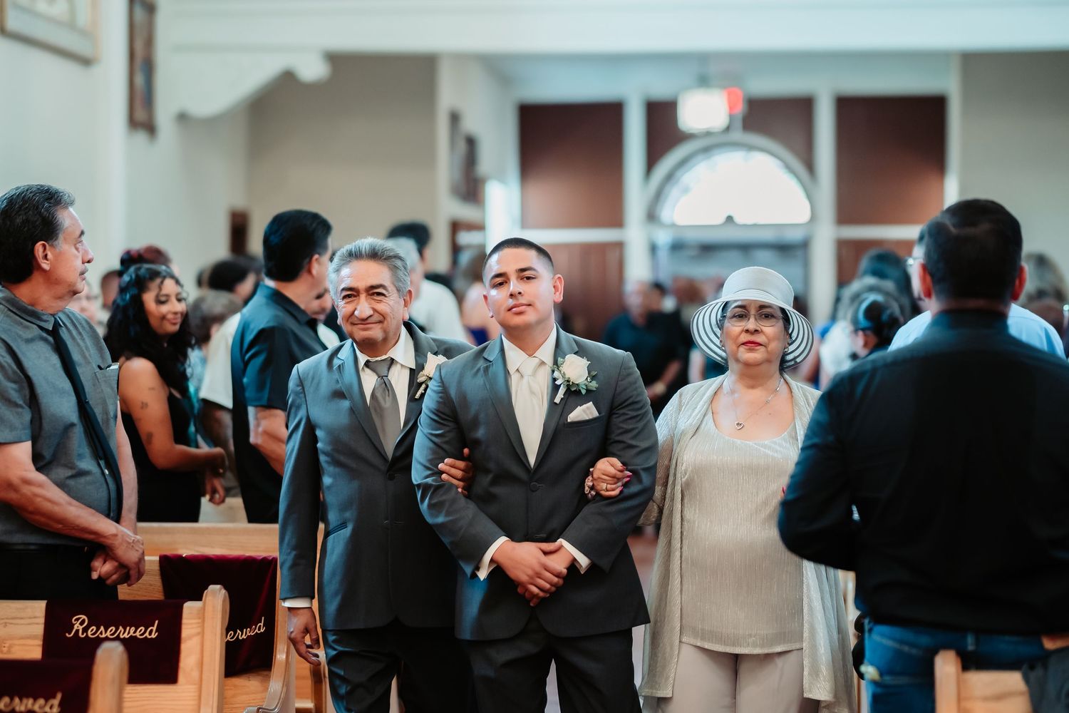 At a wedding ceremony, attendees stand together in a church while creating a celebratory atmosphere.